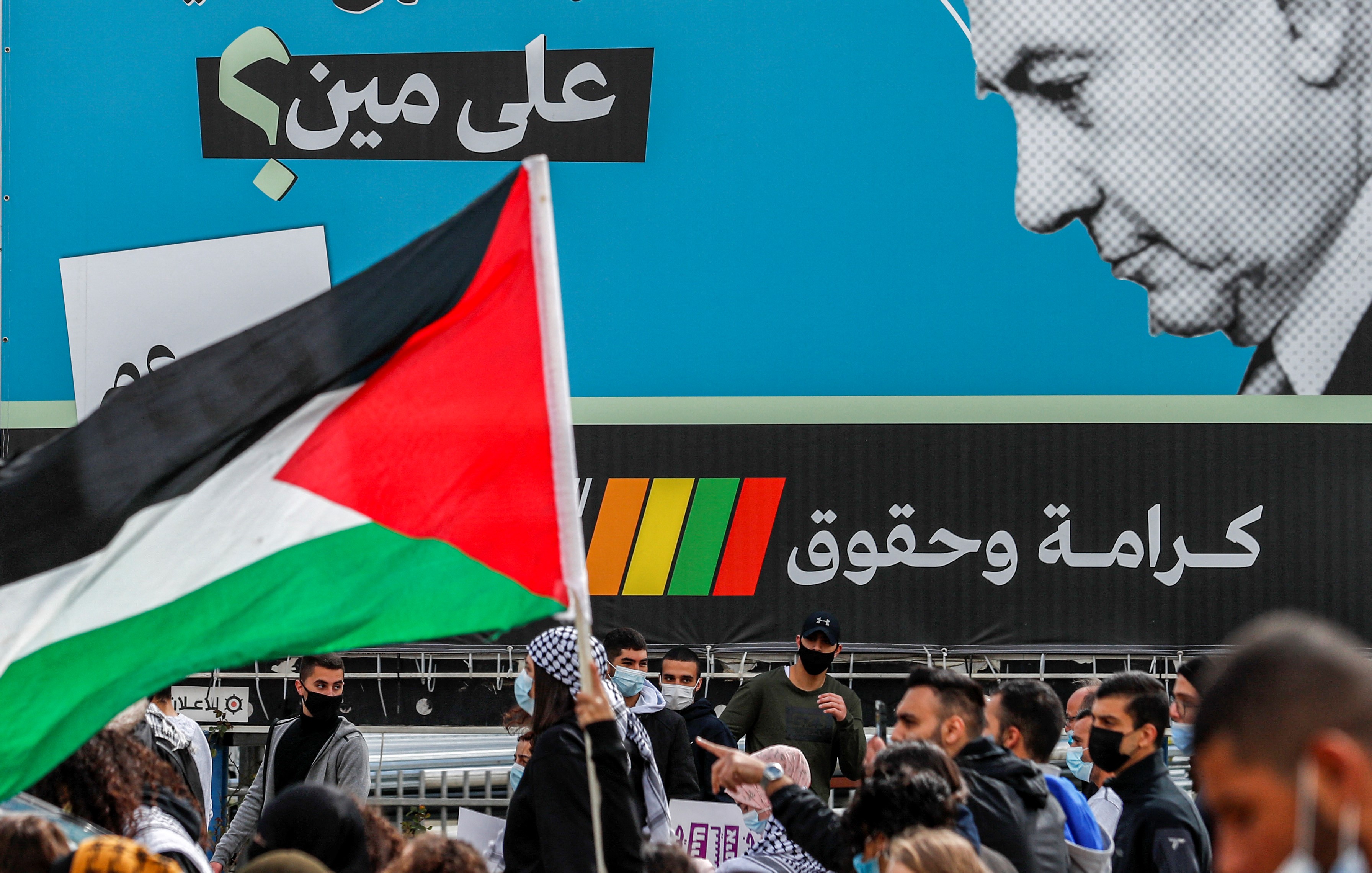 A demonstrator holds a Palestinian flag near an electoral billboard by the predominantly Arab Israeli electoral alliance the Joint List depicting Israeli prime minister Benjamin Netanyahu with a caption reading in Arabic 
