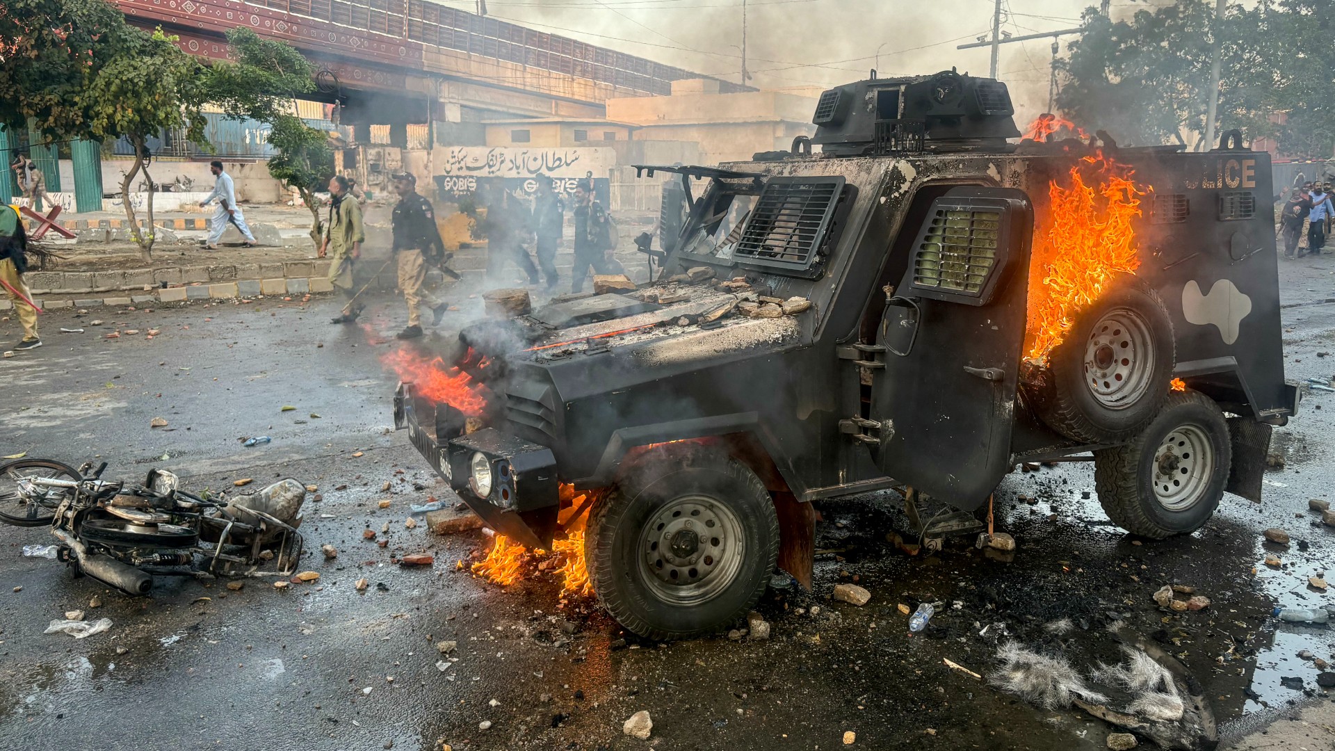 Police walk past a burning armoured vehicle set on fire by protestors outside the US consulate in Karachi after the killing of Iran's Supreme Leader Ayatollah Ali Khamenei, on 1 March 2026 (STR/AFP)