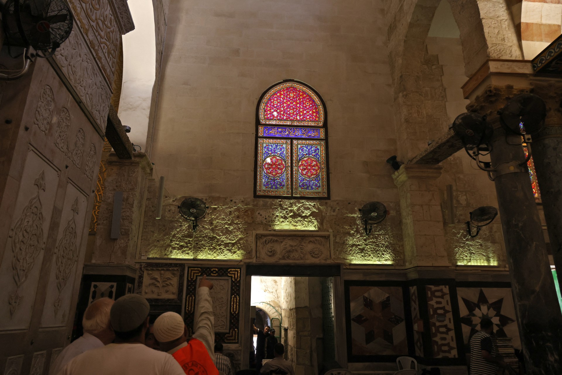 Palestinians point at a window of al-Aqsa Mosque broken by Israeli forces as they stormed the holy site (AFP)