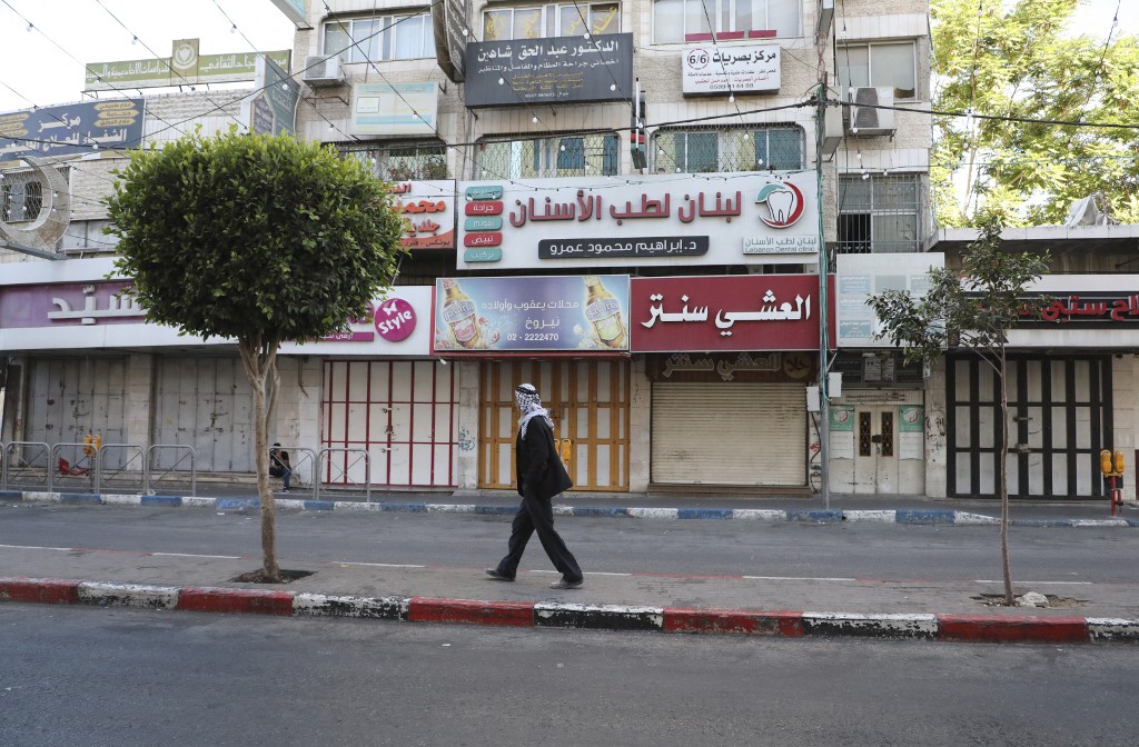 A man walks past shuttered Palestinian stores in Hebron city, as a general strike is observed in the occupied West Bank and Arab Israeli cities in solidarity with Gaza and Jerusalem, on May 18, 2021.