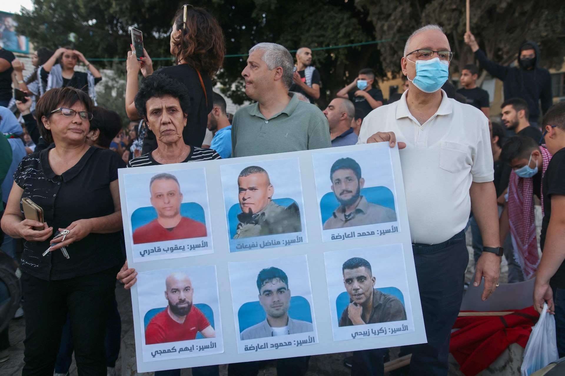Protesters lift a placard depicting the six Palestinian prisoners, as they demonstrate to support them in the northern Israeli city of Nazareth, on 11 September (AFP)