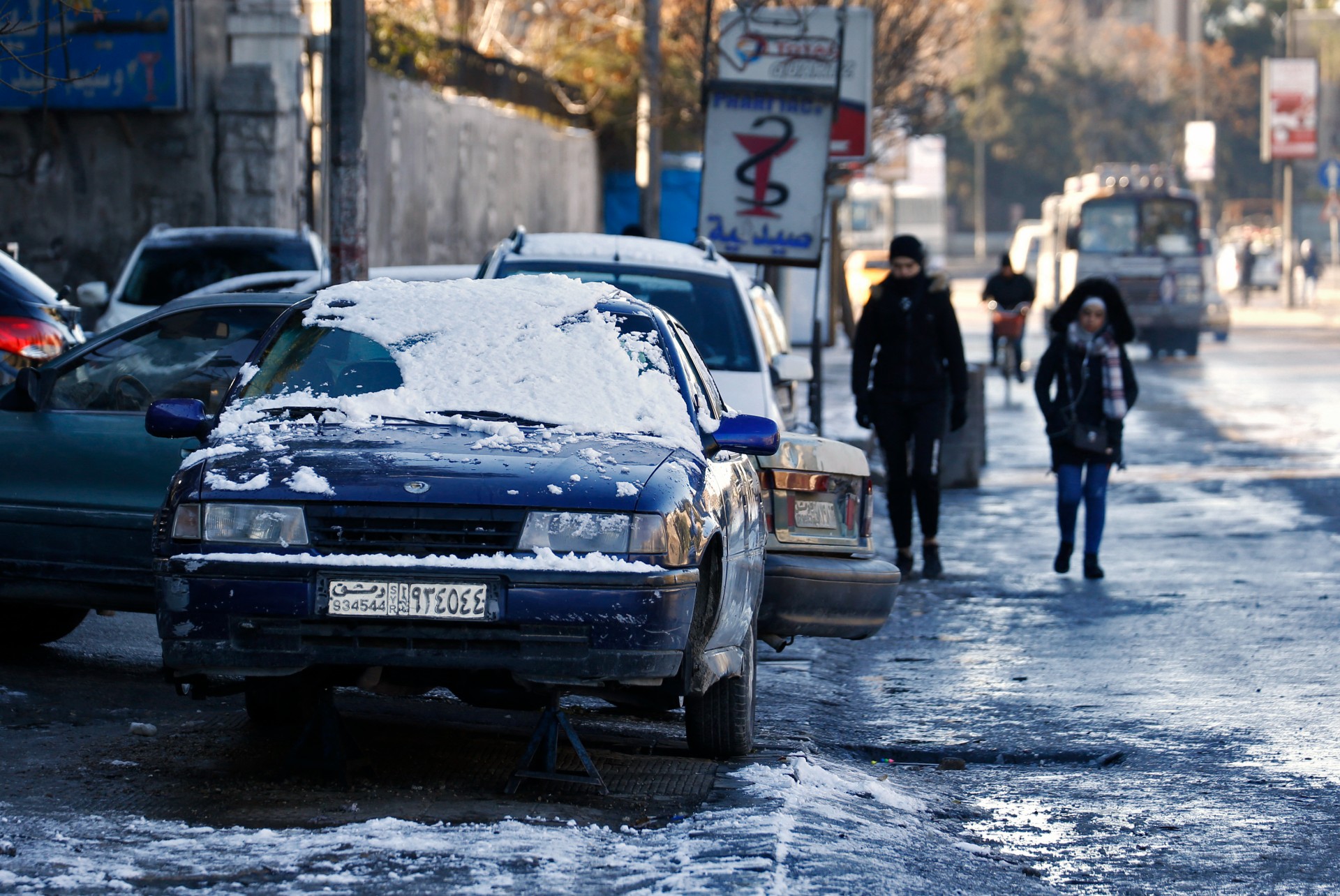 Syrians walk on a snow covered area in Damascus on 20 January, 2022 (AFP)