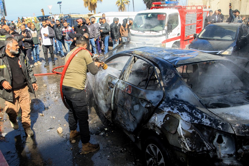A firefighter extinguishes the husk of a destroyed vehicle that was targeted by Israeli bombardment in Lebanon's southern coastal city of Sidon on March 18, 2026.