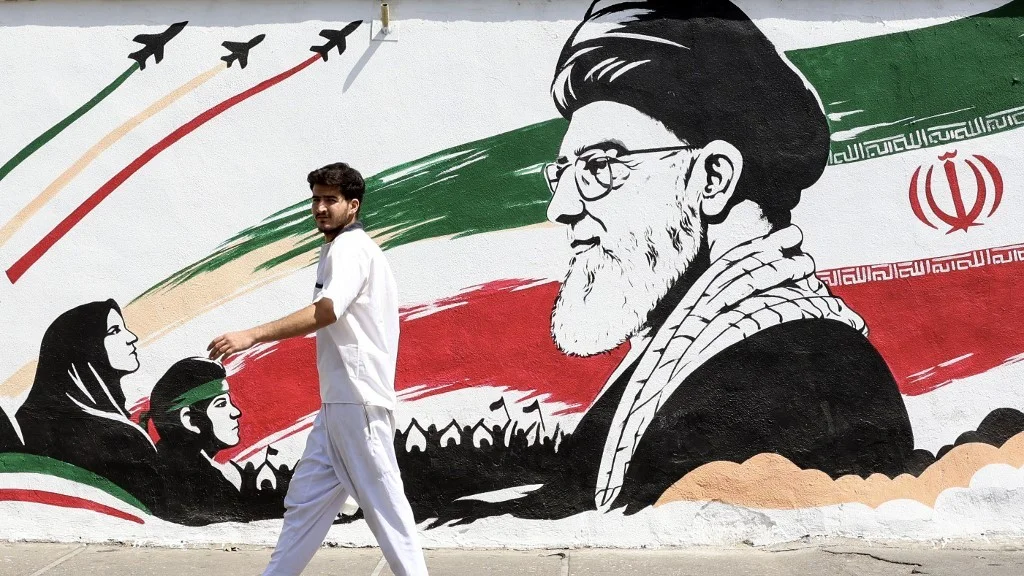 A man walks past a mural depicting late Iranian supreme leader Ayatollah Ali Khamenei in Tehran on 24 July 2026 (AFP)
