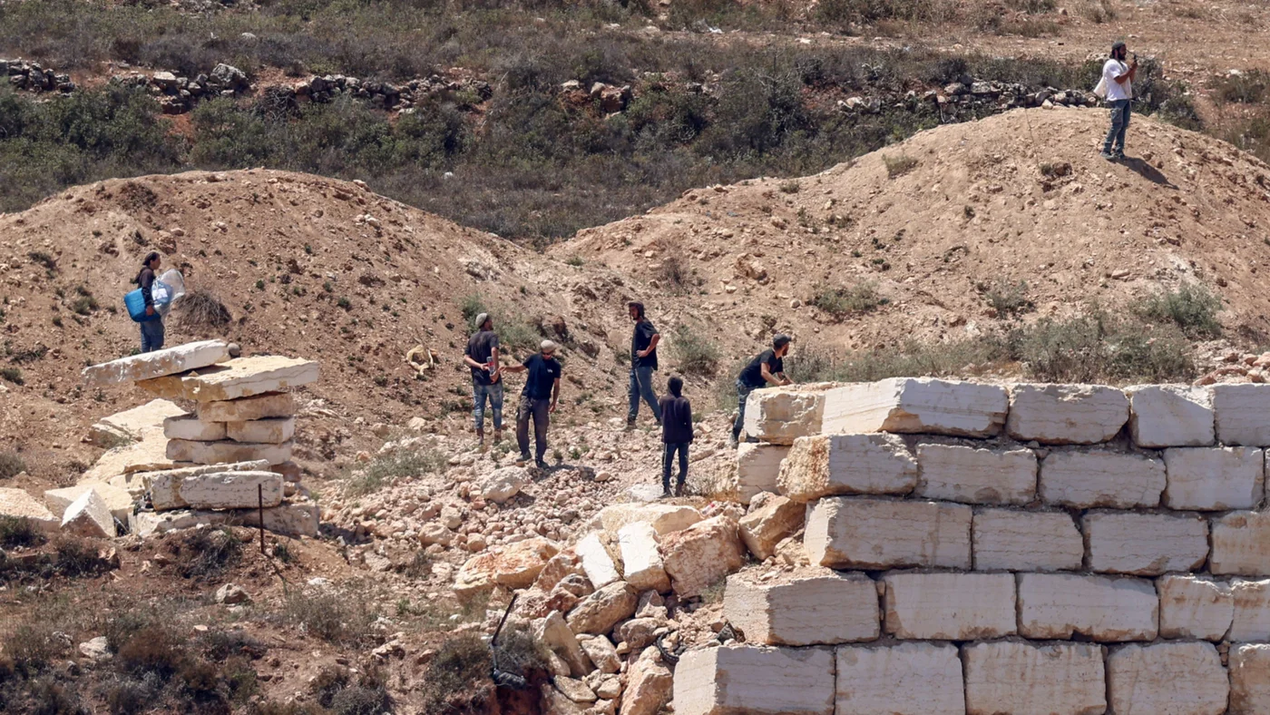 Israeli settlers gather in front of Palestinian houses in the village of Qusra, south of Nablus, in the occupied West Bank, on 12 August 2026 (Zain Jaafar/AFP)