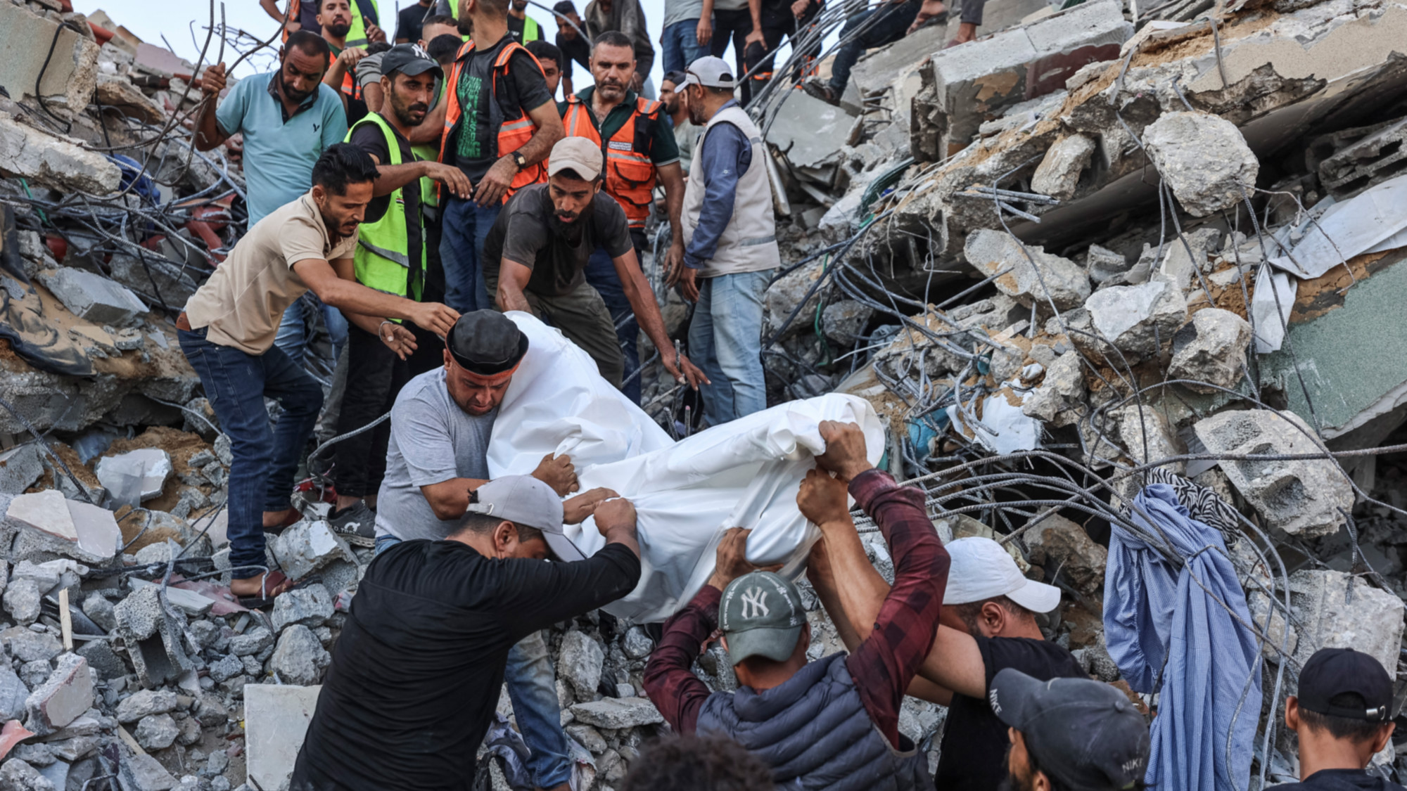 Volunteers and rescuers carry a body recovered from the rubble of a collapsed building in  Gaza City on 16 September 2026 (AFP/Omar al-Qattaa)