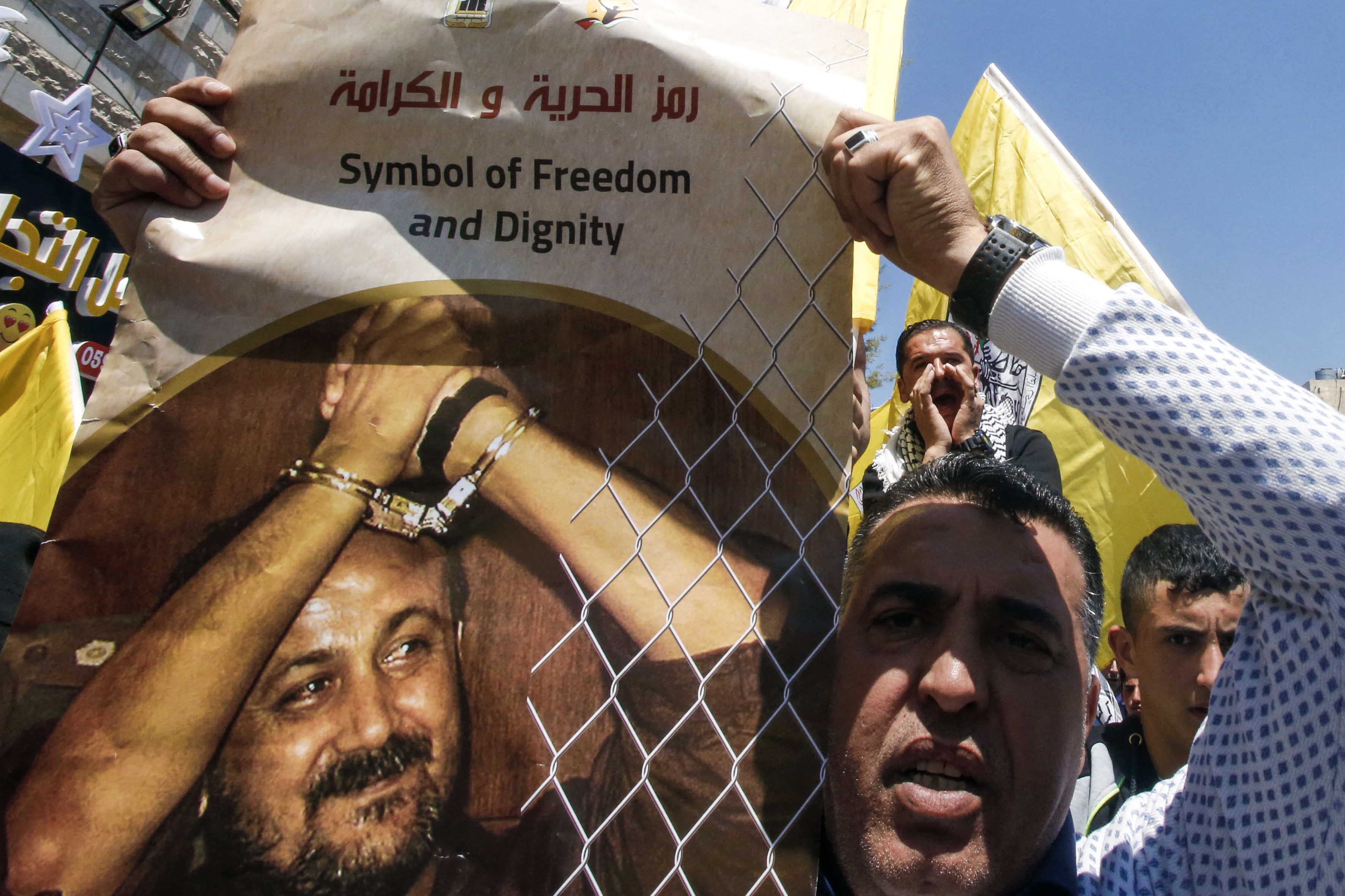 A man holds a photo of prominent Palestinian prisoner Marwan Barghouti calling for his release during a rally supporting those detained in Israeli jails after hundreds of them launched a hunger strike, in the West Bank town of Hebron on April 17, 2017