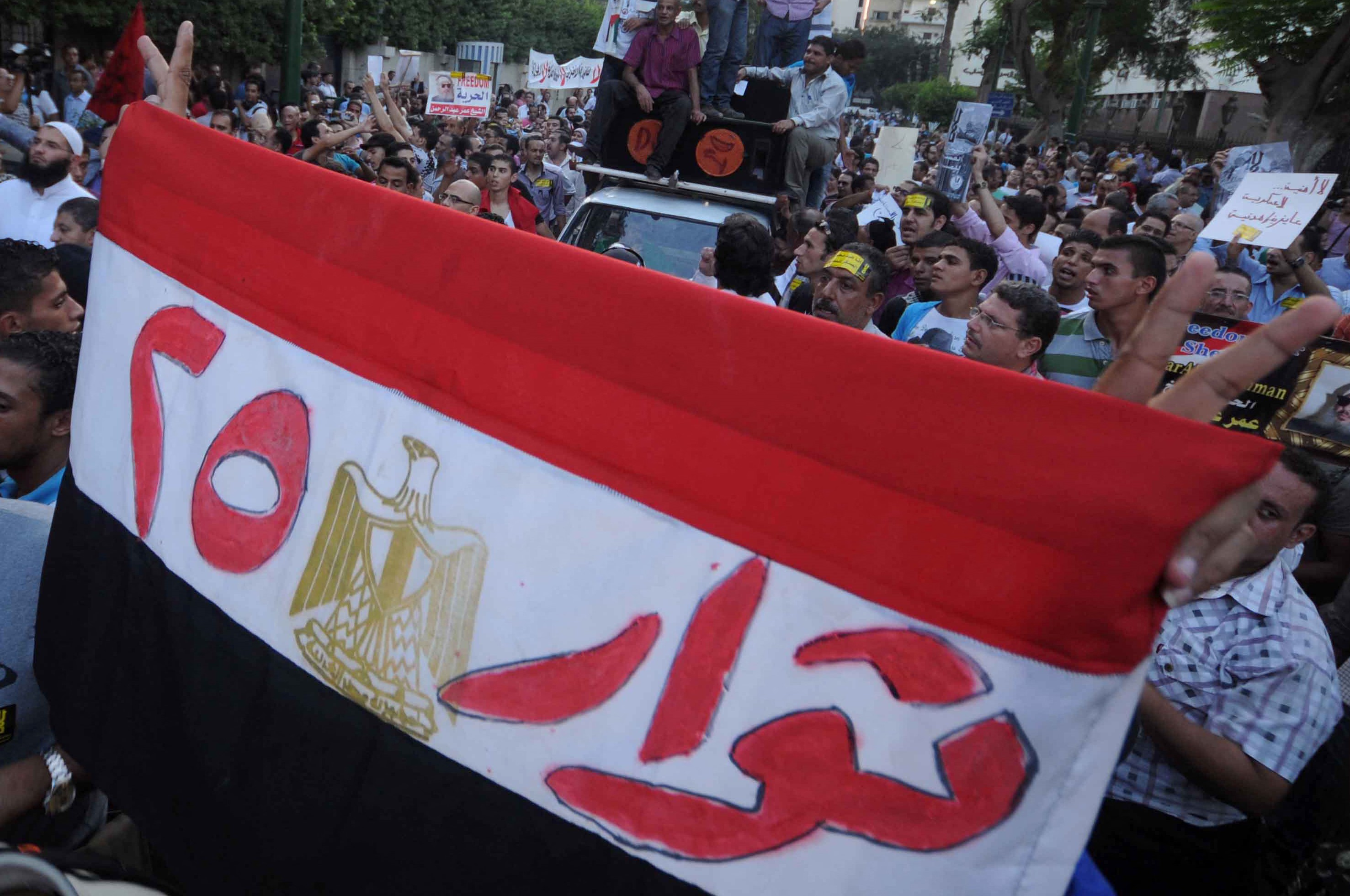 An Egyptian protester holds his national flag bearing the slogan 