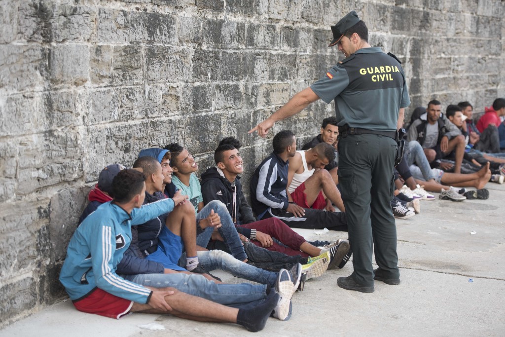 A Spanish guard speaks with Moroccan and Sub-Saharan migrants in 2017 (AFP)