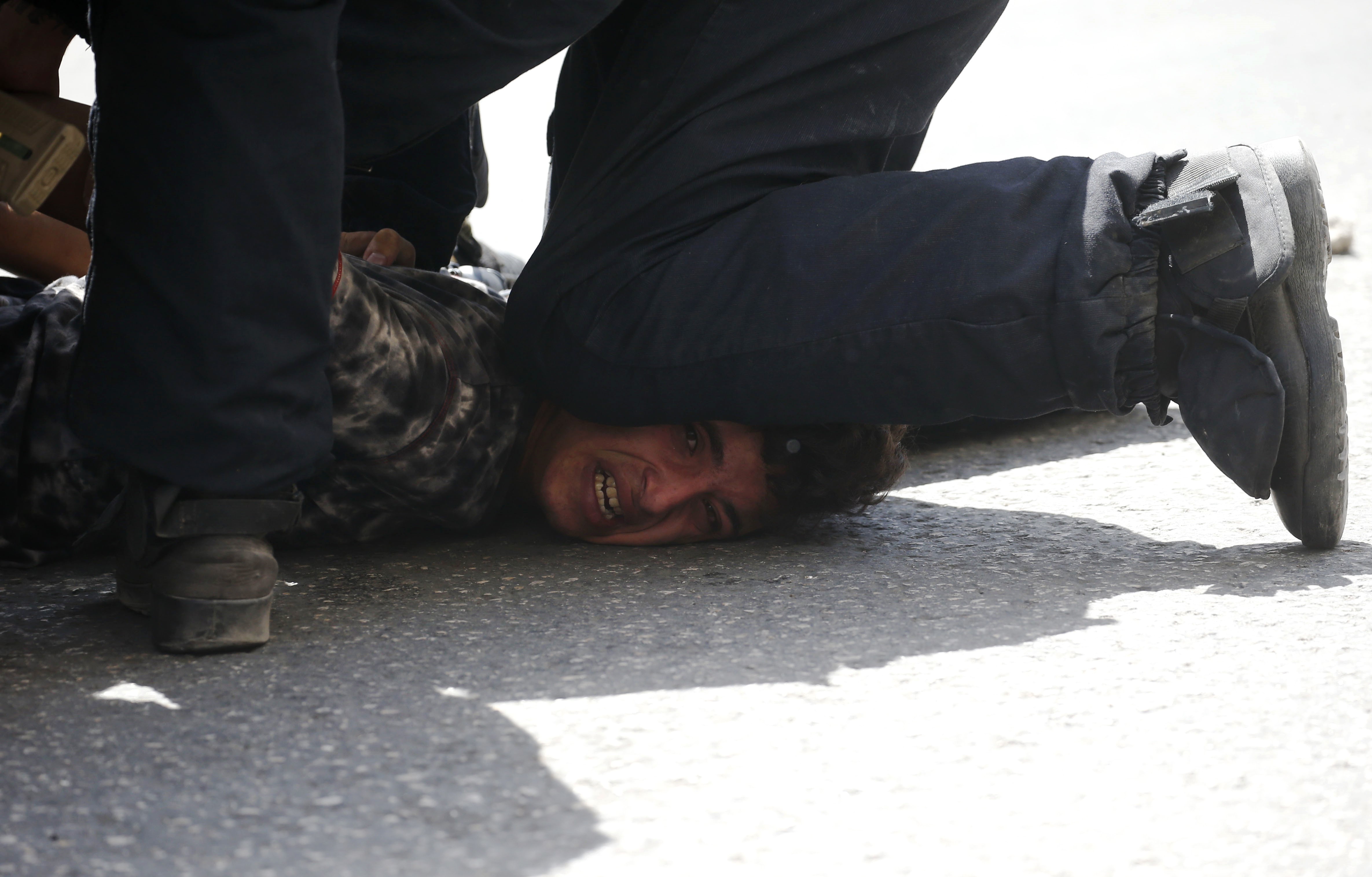 An Israeli soldier uses his knee to pin down and arrest a Palestinian youth in Hebron on 28 July, 2017 (AFP)