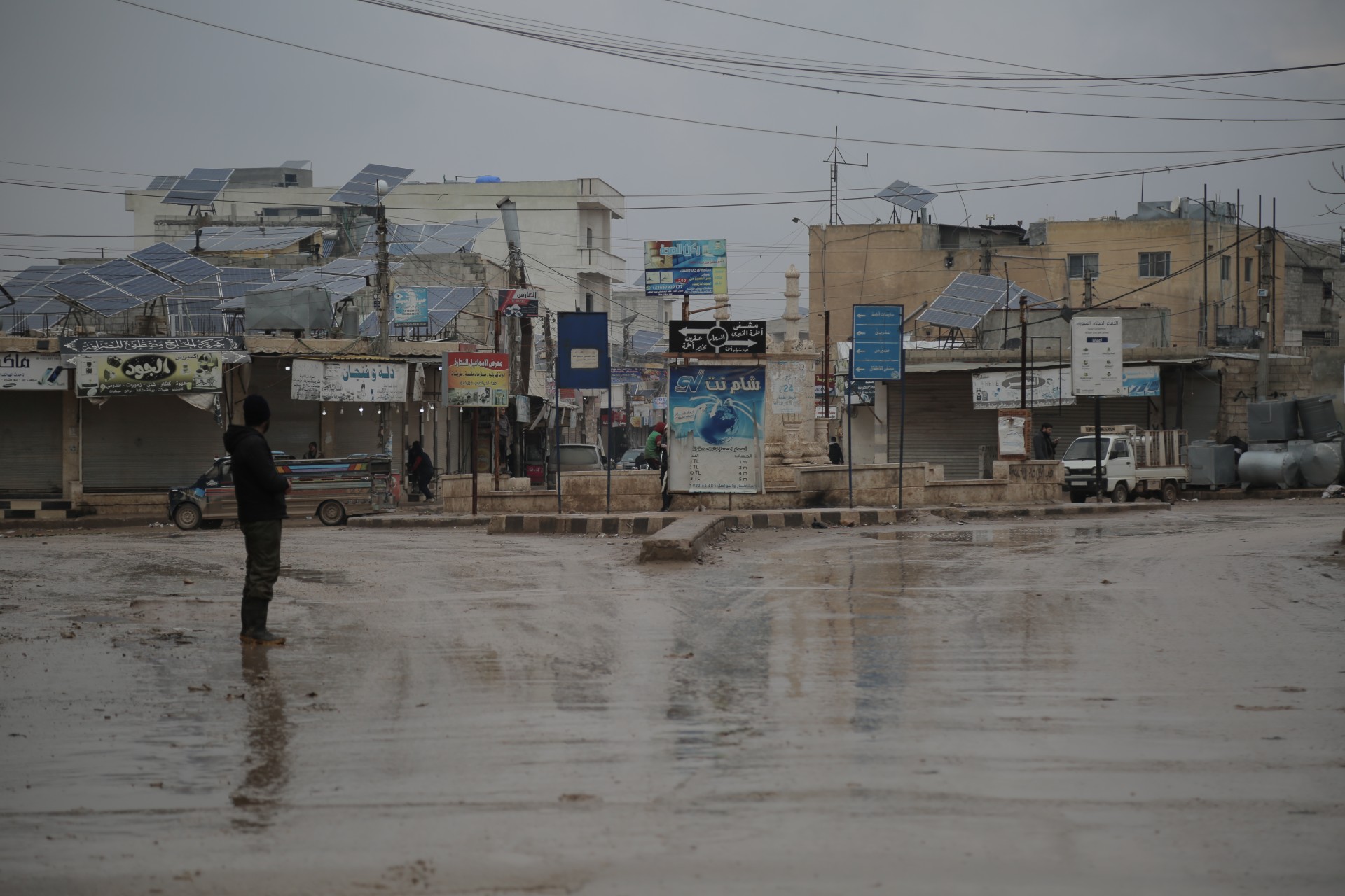 A man stands in the main square of the village of Atmeh in northwest Syria, where shops close their doors before the Zuhr prayer (MEE/Bilal al-Hammoud)