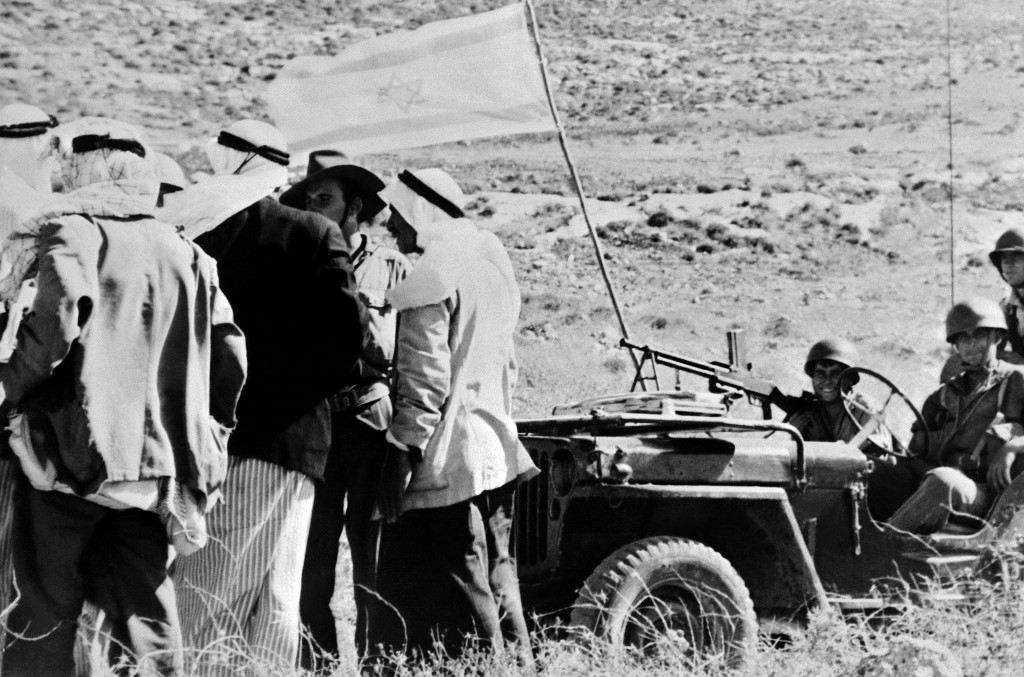 Palestinians speak with Israeli soldiers by a captured Arab village in 1948 (AFP)