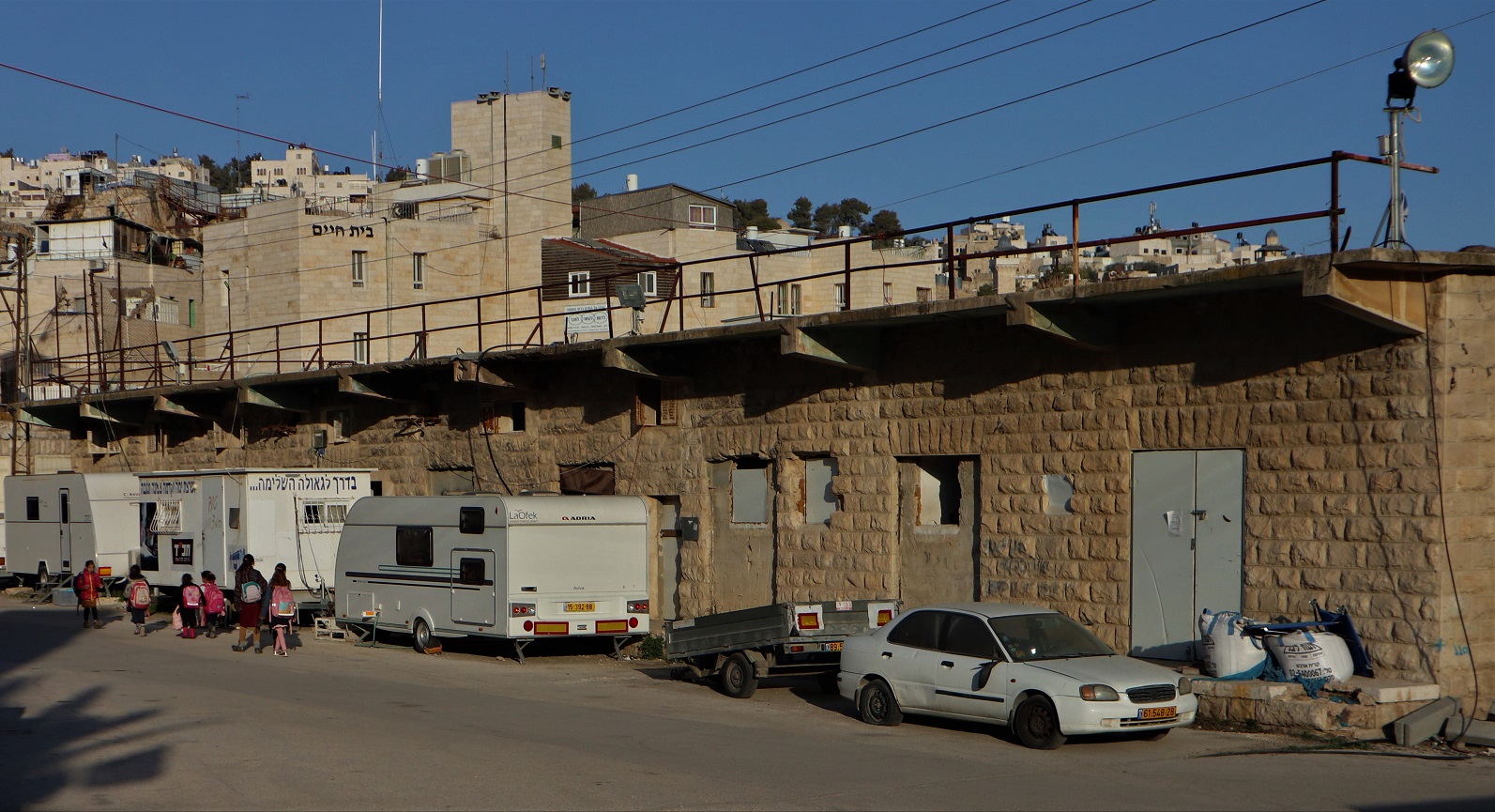 Des enfants israéliens passent devant l’ancien marché aux légumes dans la vieille ville d’Hébron, que le ministère de la Défense israélien envisage de démolir pour construire des logements pour colons (MEE/Marie Niggli)