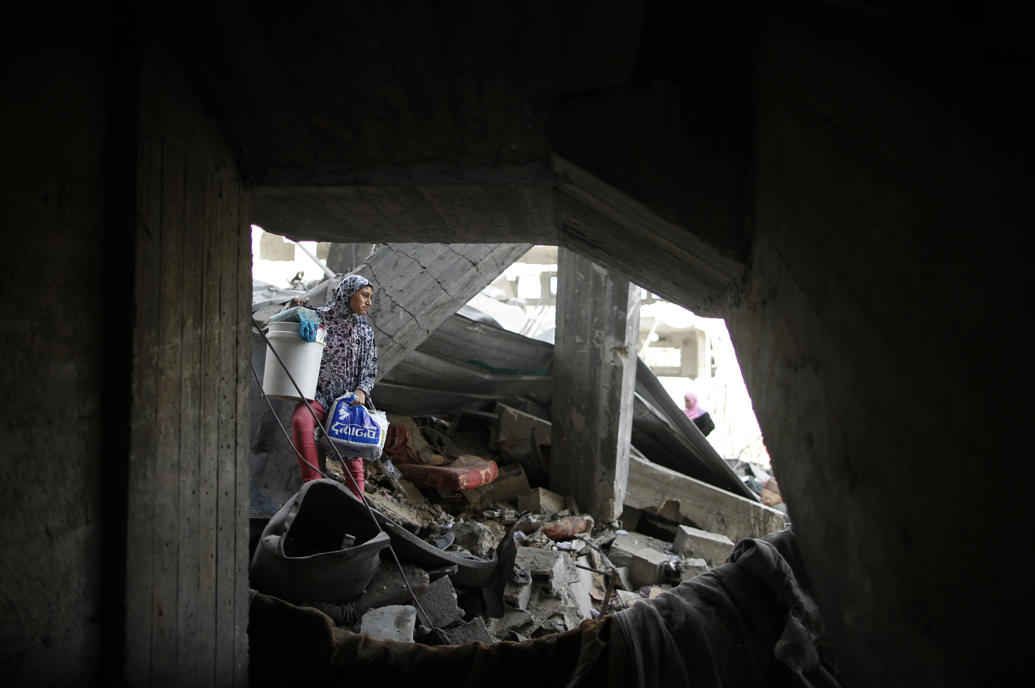 A Palestinian girl carries her belongings from her family's destroyed house in the Shejaia neighbourhood on 26 July 2014. (Reuters)