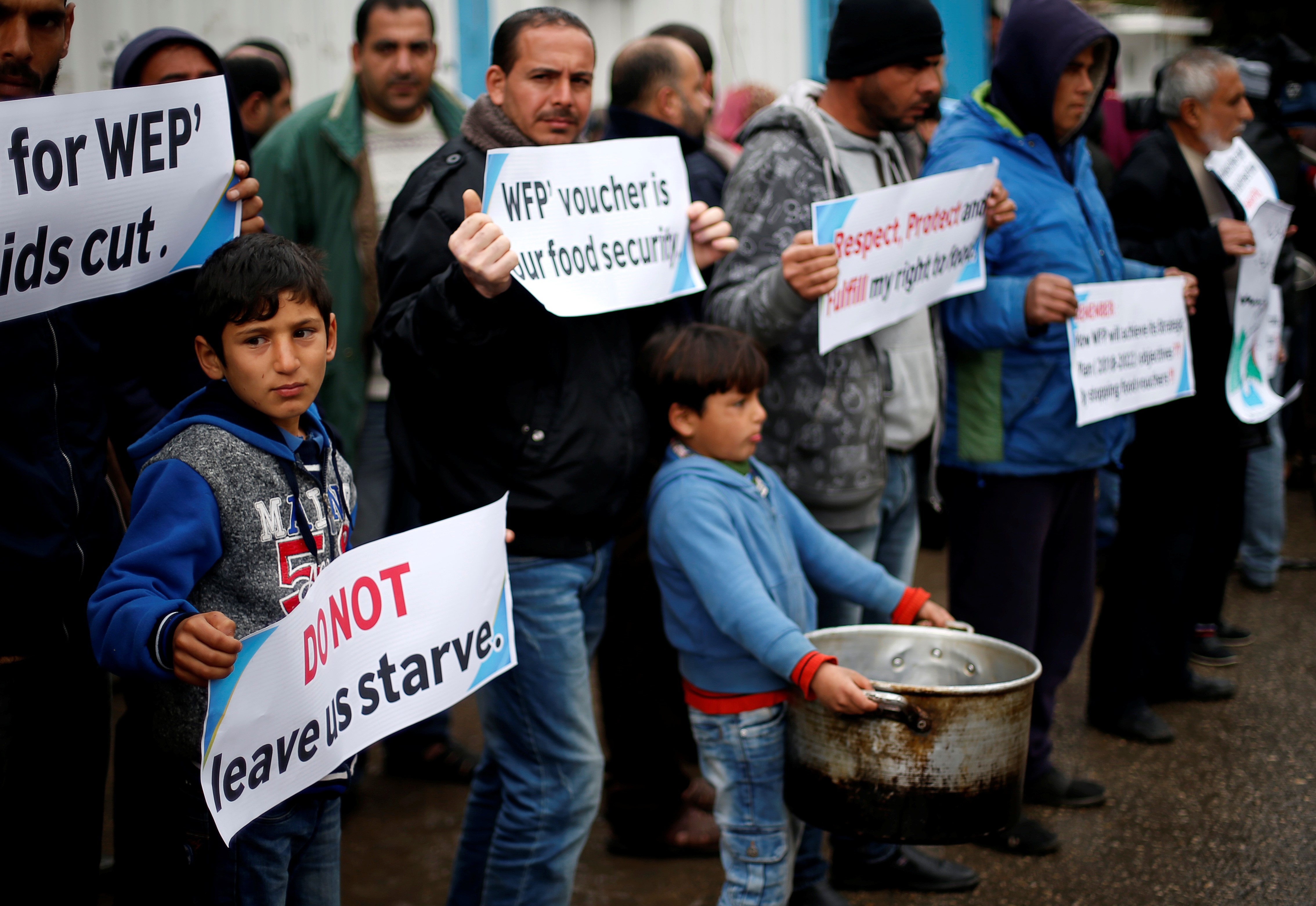 Palestinians hold signs during a protest against aid cut, outside United Nations' offices in Gaza City on 17 January, 2018 (Reuters)