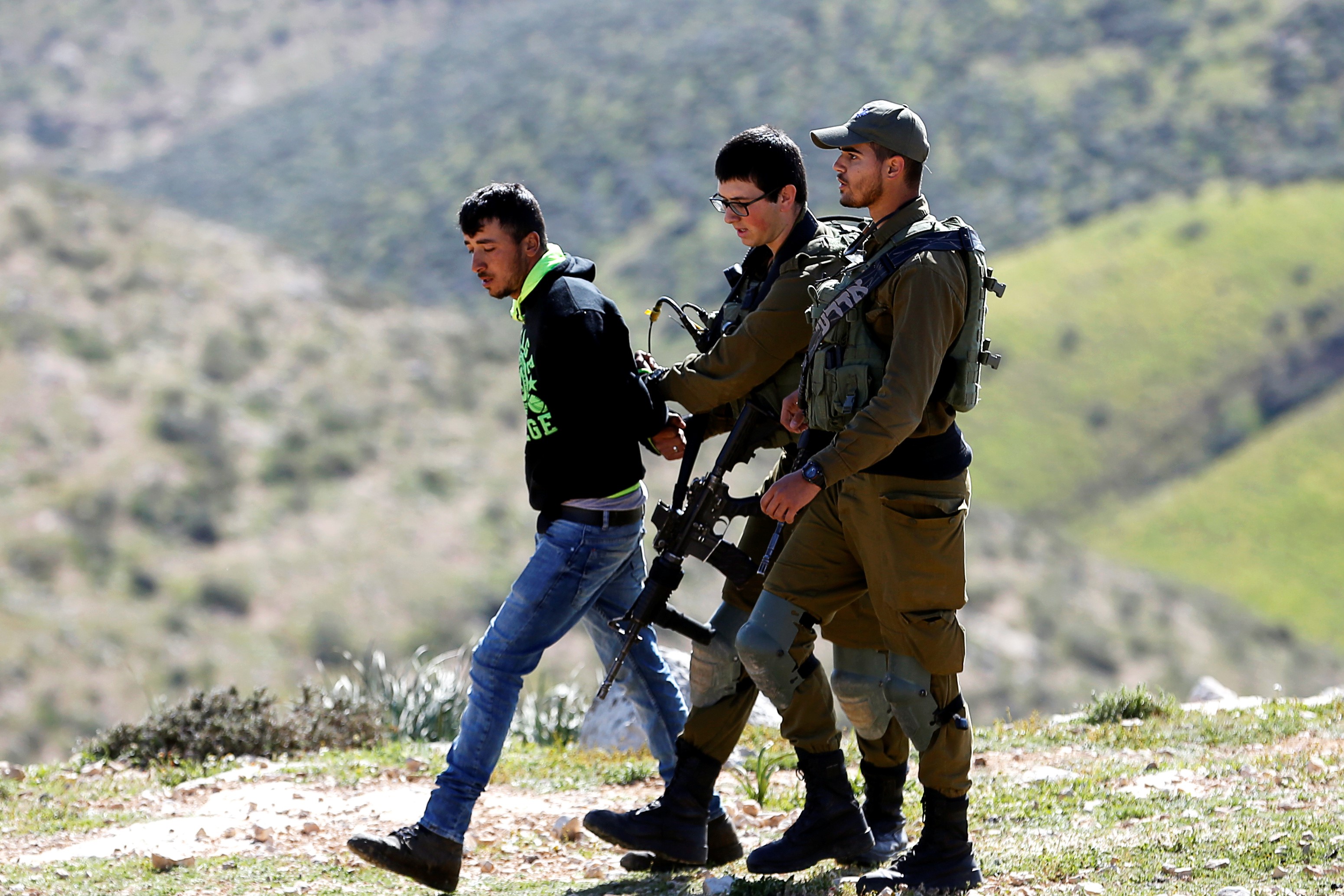   Israeli soldiers detain a Palestinian during the demolishing of his house that army told them they didn’t obtain a construction license, near Yatta in the Israeli-occupied West Bank on 20 March (Reuters)