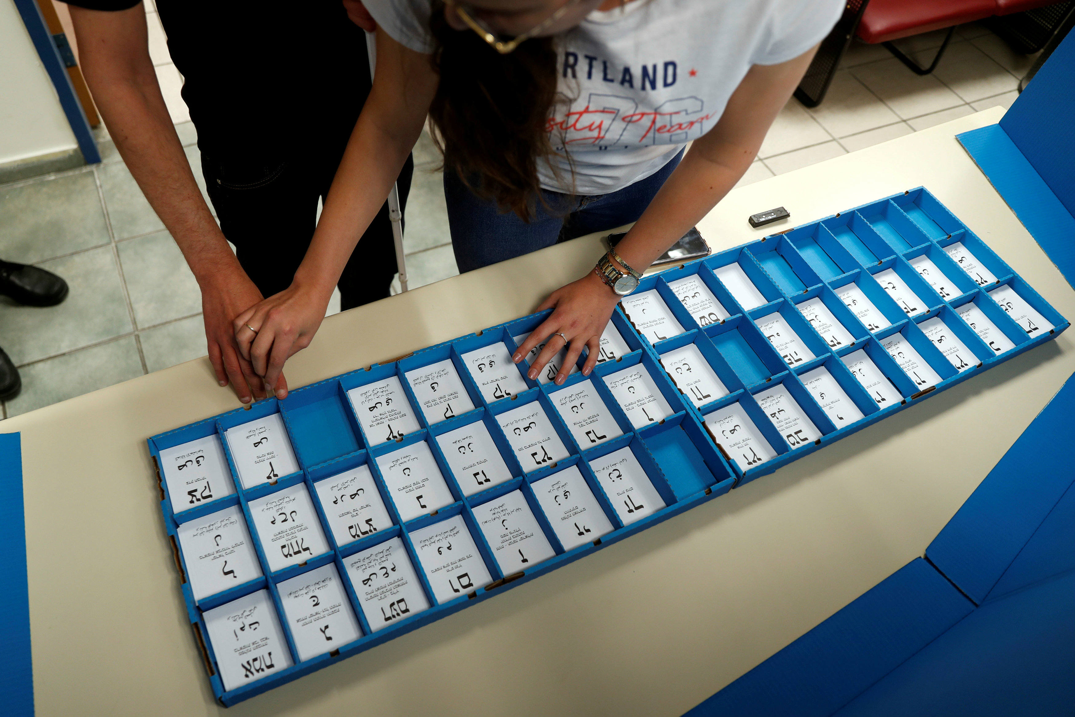 A blind man touches ballot papers during a training session with a guide who teaches him how to vote using a wearable device by OrCam, which provides visual aid for visually impaired people (Reuters)