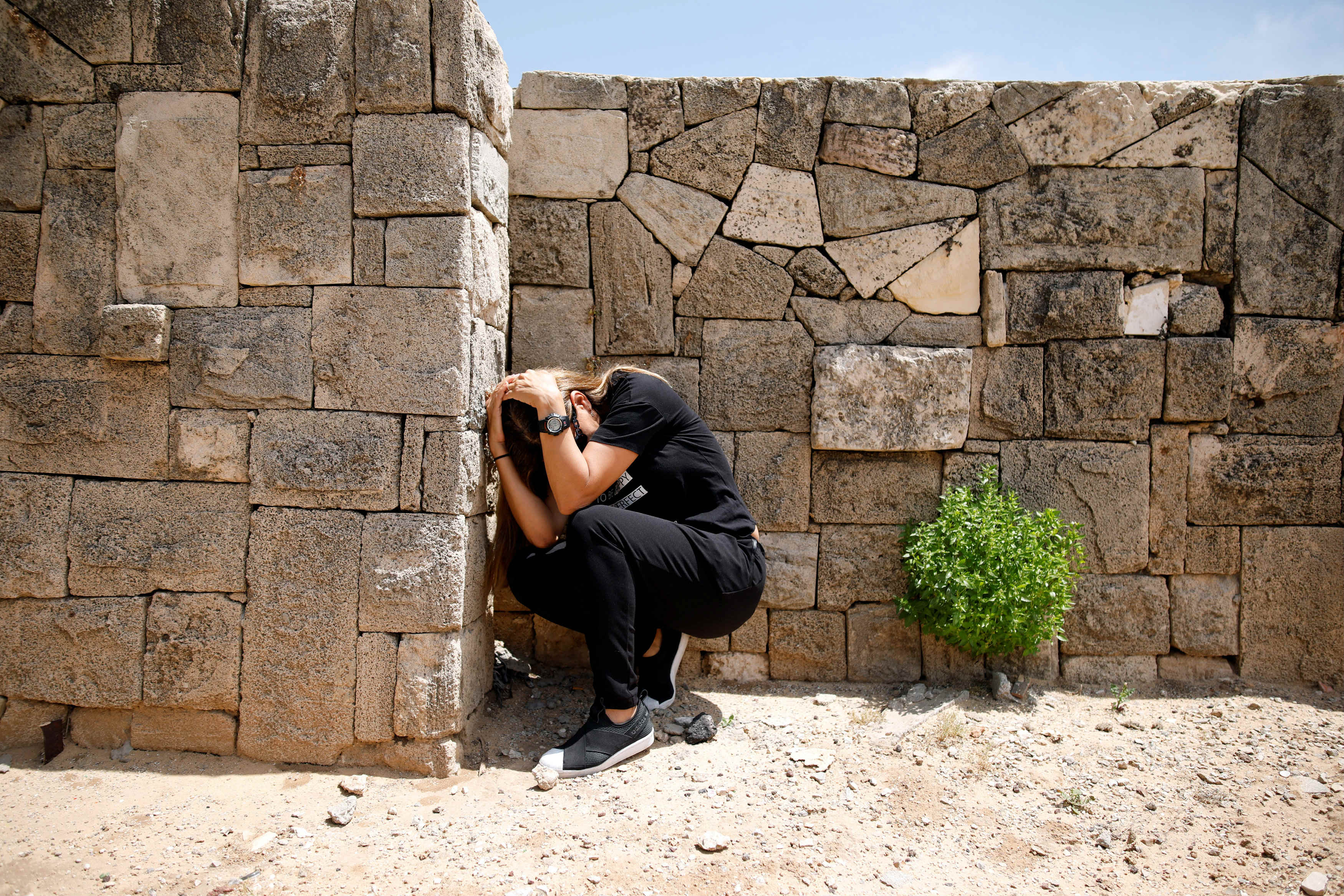An Israeli takes cover as a siren sounds warning of incoming rockets from Gaza, during cross-border hostilities, in the southern Israeli city of Ashkelon (Reuters)
