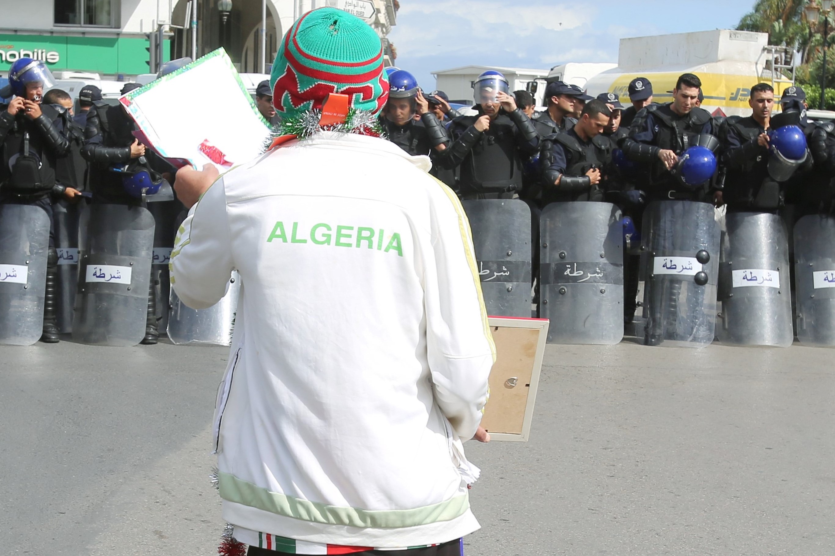 A demonstrator gestures near police officers standing guard during a protest against the country's ruling elite on 15 October (Reuters)