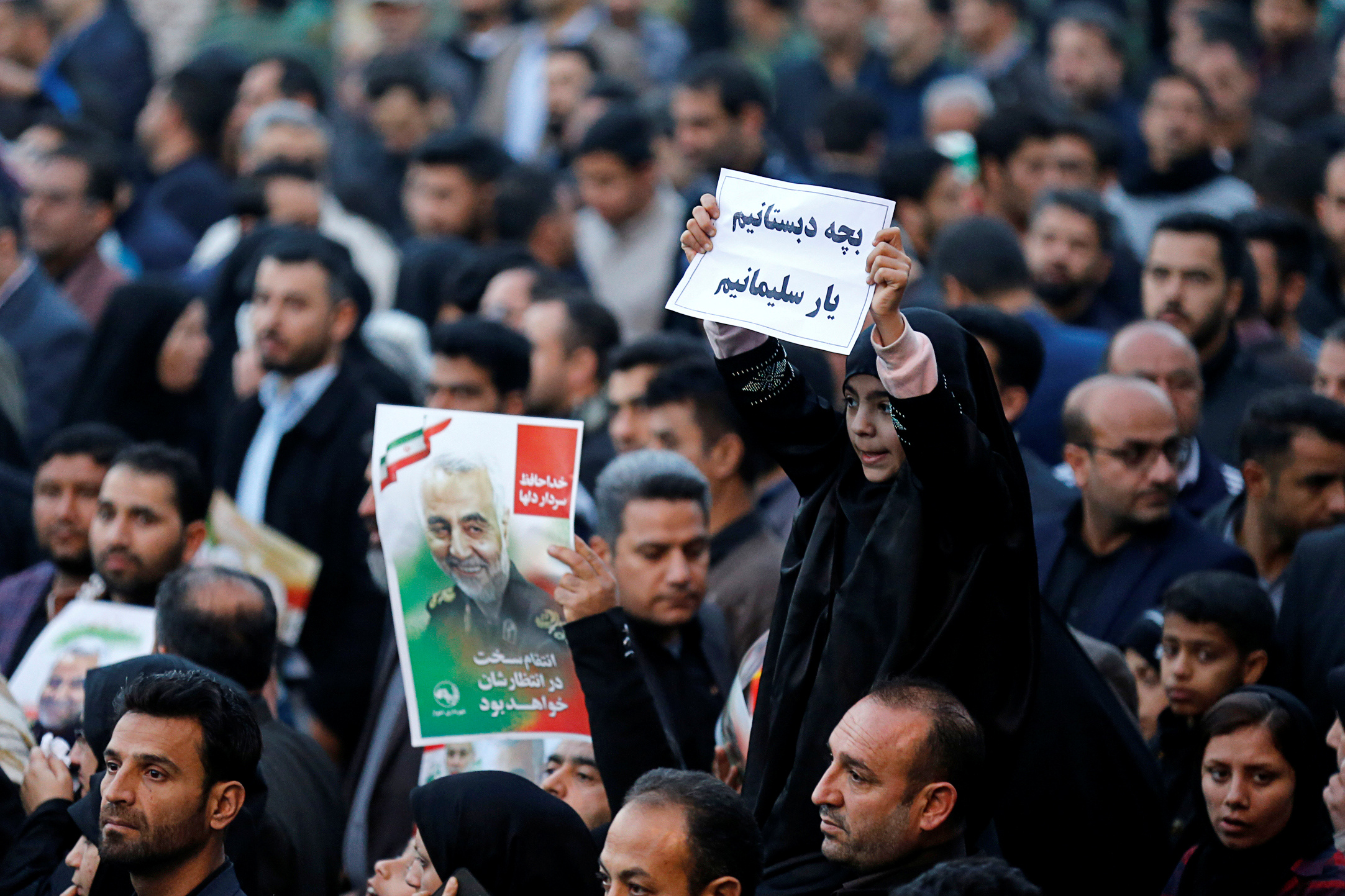 Girl holds up sign during a funeral procession for Soleimani and al-Muhandis, in Ahvaz (Reuteres)