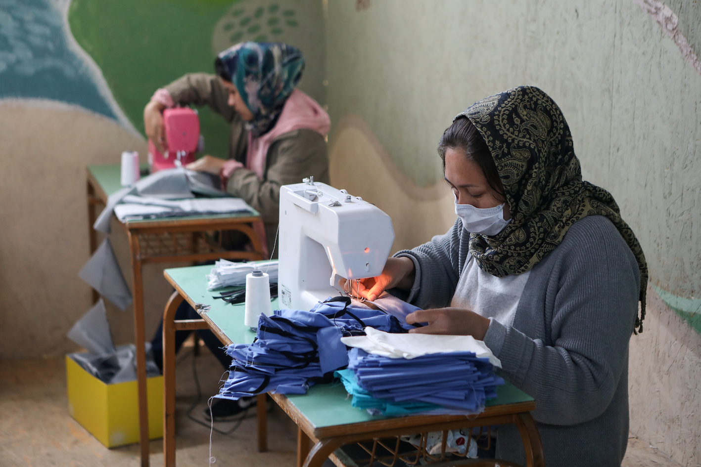 Refugees from the Moria camp sew handmade protective masks after a covid-19 case was reported in Lesbos (Reuters)