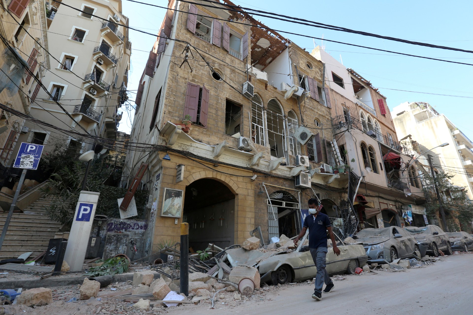 A man wearing a protective face mask walks past damaged buildings and vehicles in Gemmayzeh near the site of Tuesday's blast (Reuters)