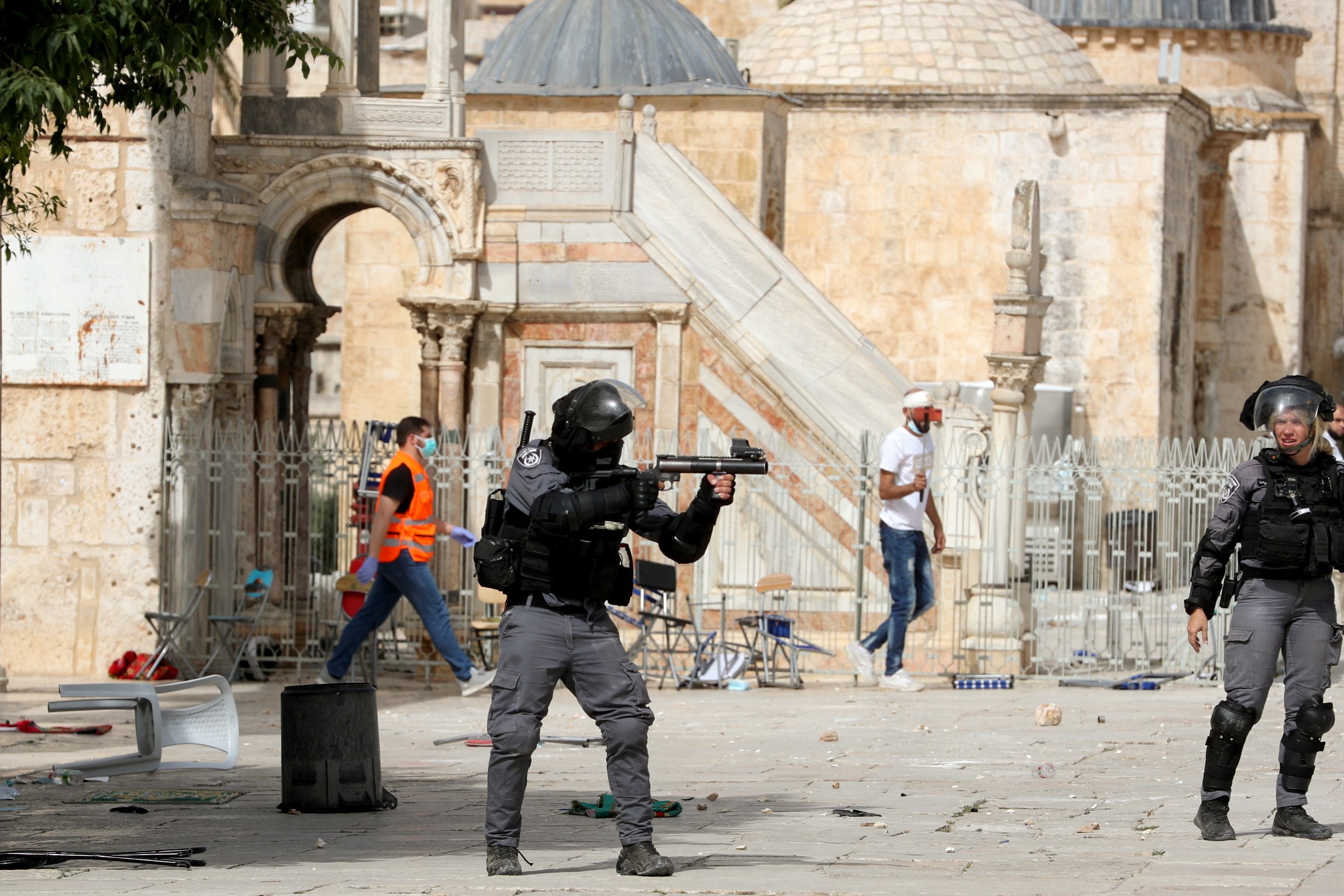 A member of Israeli police aims a weapon at Palestinians in al-Aqsa Mosque (Reuters)