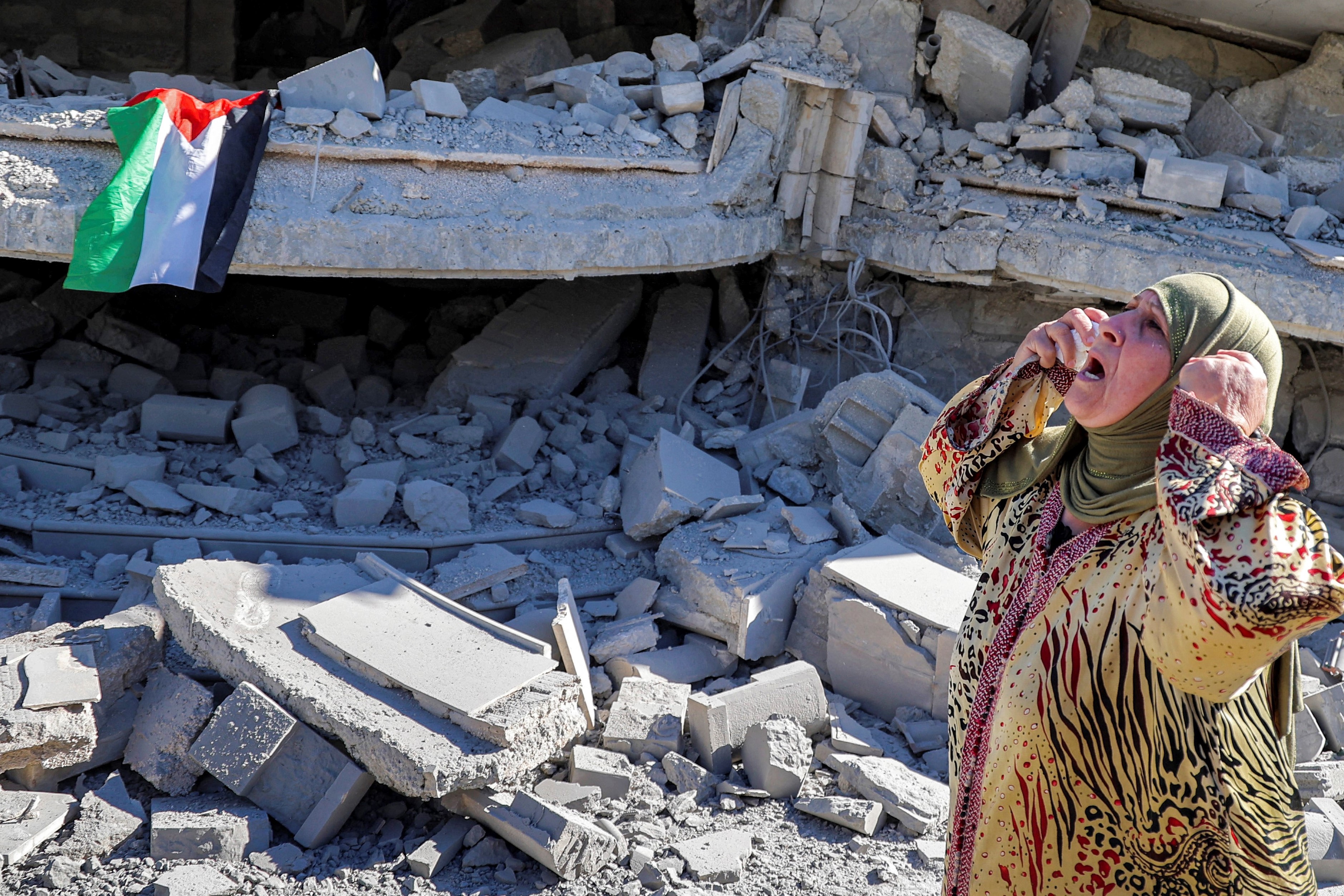 A Palestinian woman reacts outside a building that belonged to Montasser Shalabi that was demolished by Israeli forces (AFP)