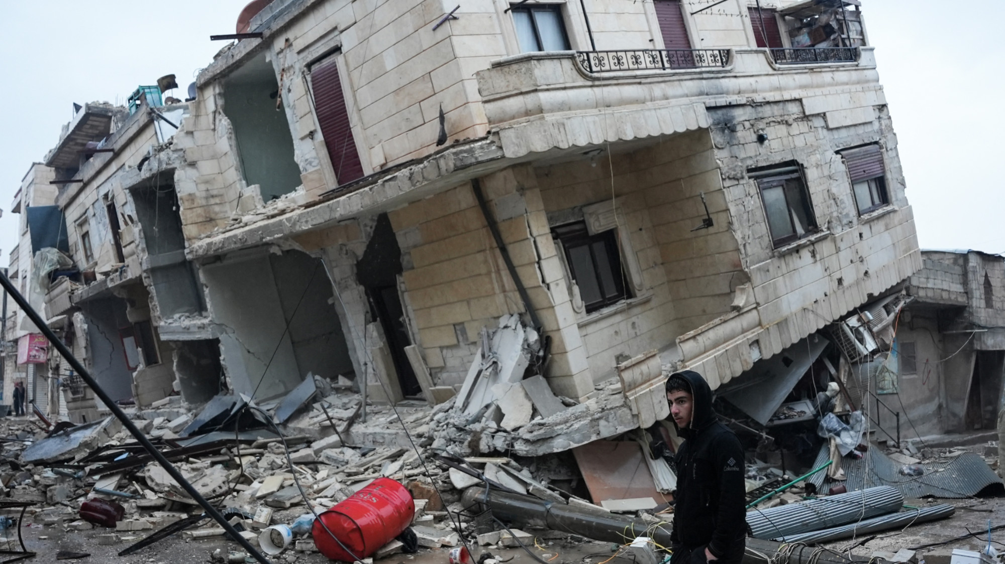 Residents stand in front of a collapsed building following an earthquake in the town of Jandaris, in the countryside of Syria's northwestern city of Afrin in the rebel-held part of Aleppo province, on Monday 6 February.