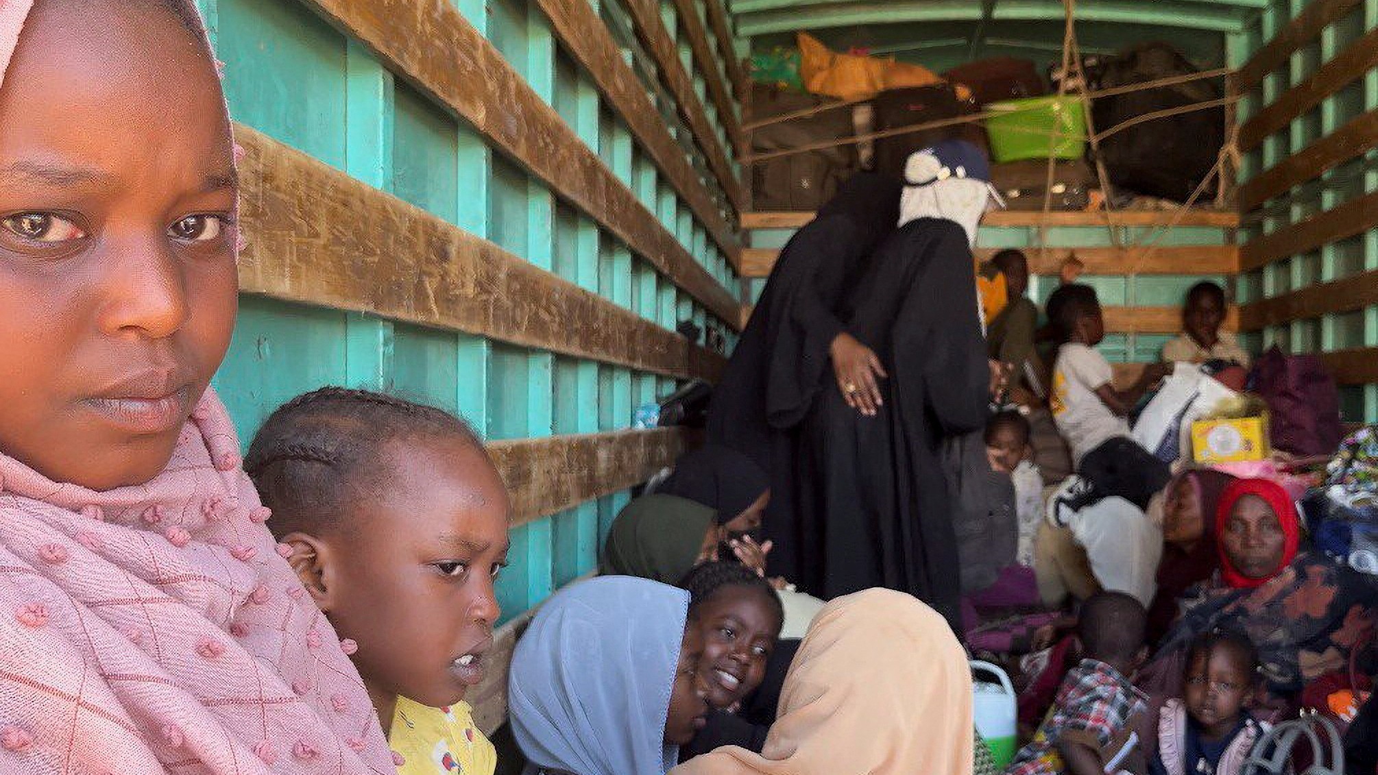 Sudanese families are seen inside a truck on their way to Egypt through the Qustul border in the Sudanese city of Wadi Halfa, on 1 May (Reuters)