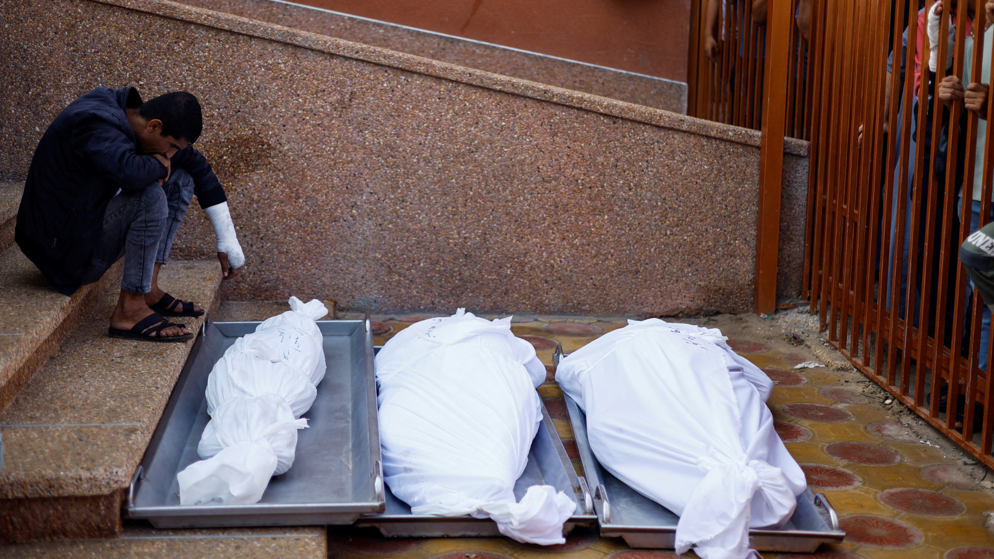 A Palestinian sits near the bodies of those killed in Israeli strikes, at Nasser hospital in Khan Younis, Gaza on 7 November 2023 (Reuters)