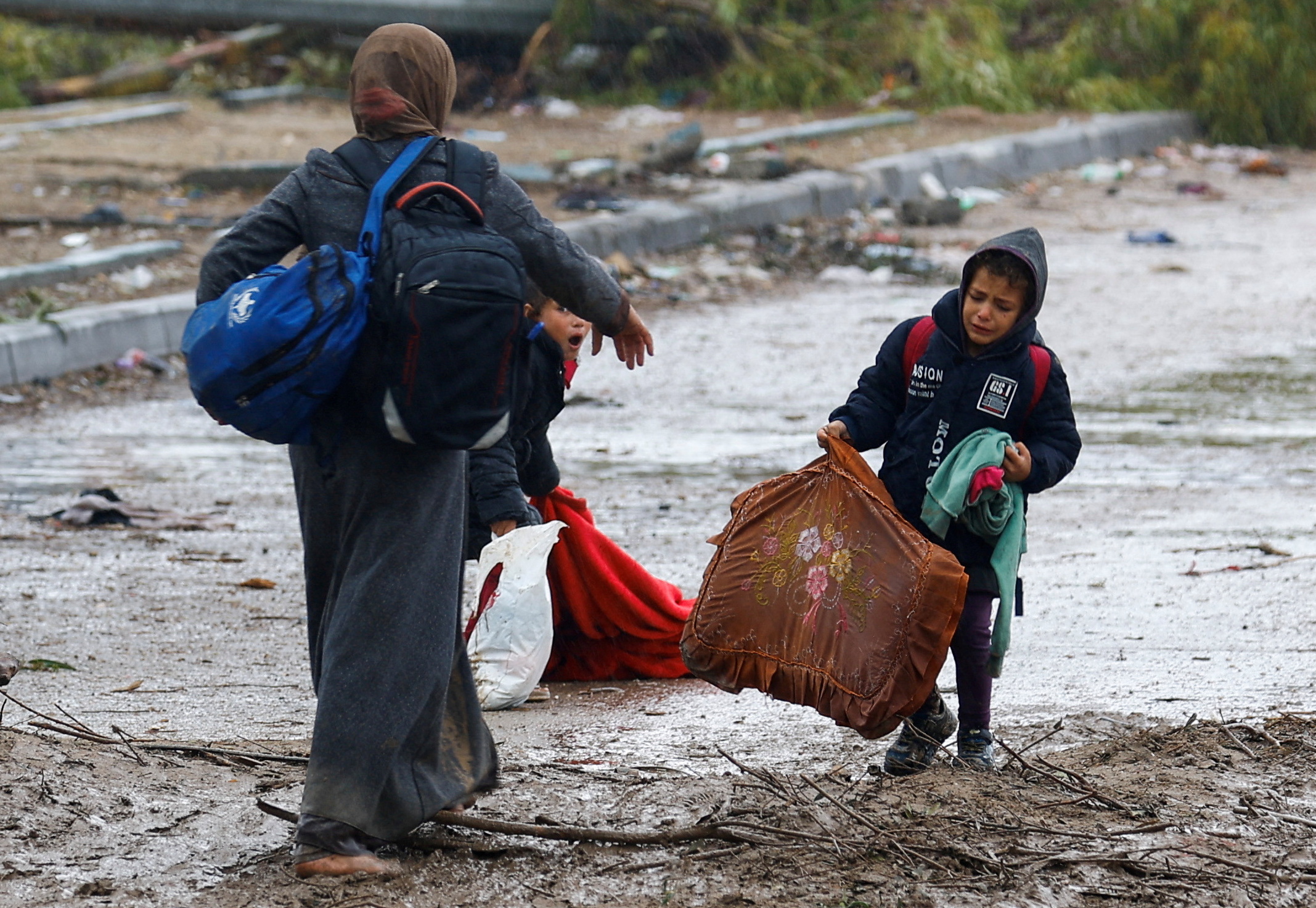 Une Palestinienne fuyant le nord de la bande de Gaza aide ses enfants à porter leurs affaires alors qu’ils se dirigent vers le sud, le 27 novembre 2023 (Reuters/Ibraheem Abu Mustafa)