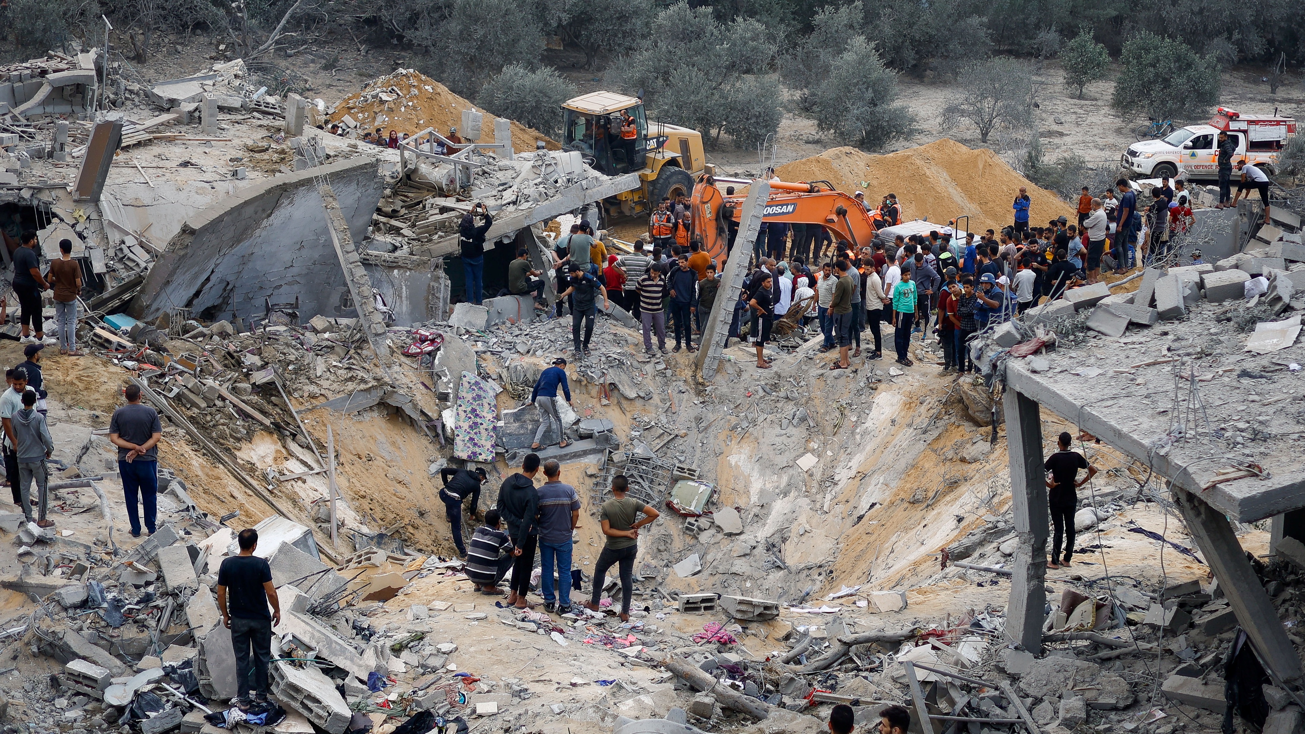 Residents look on at the epicentre of Israeli strikes on a residential building in Khan Yunis
