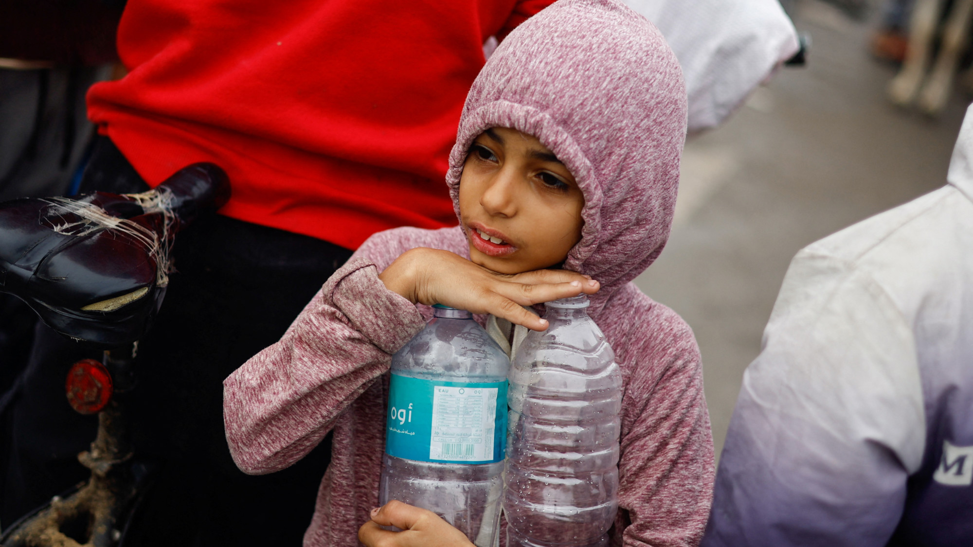 A Palestinian girl holds empty water bottles as she queues to collect water in Rafah (Reuters)