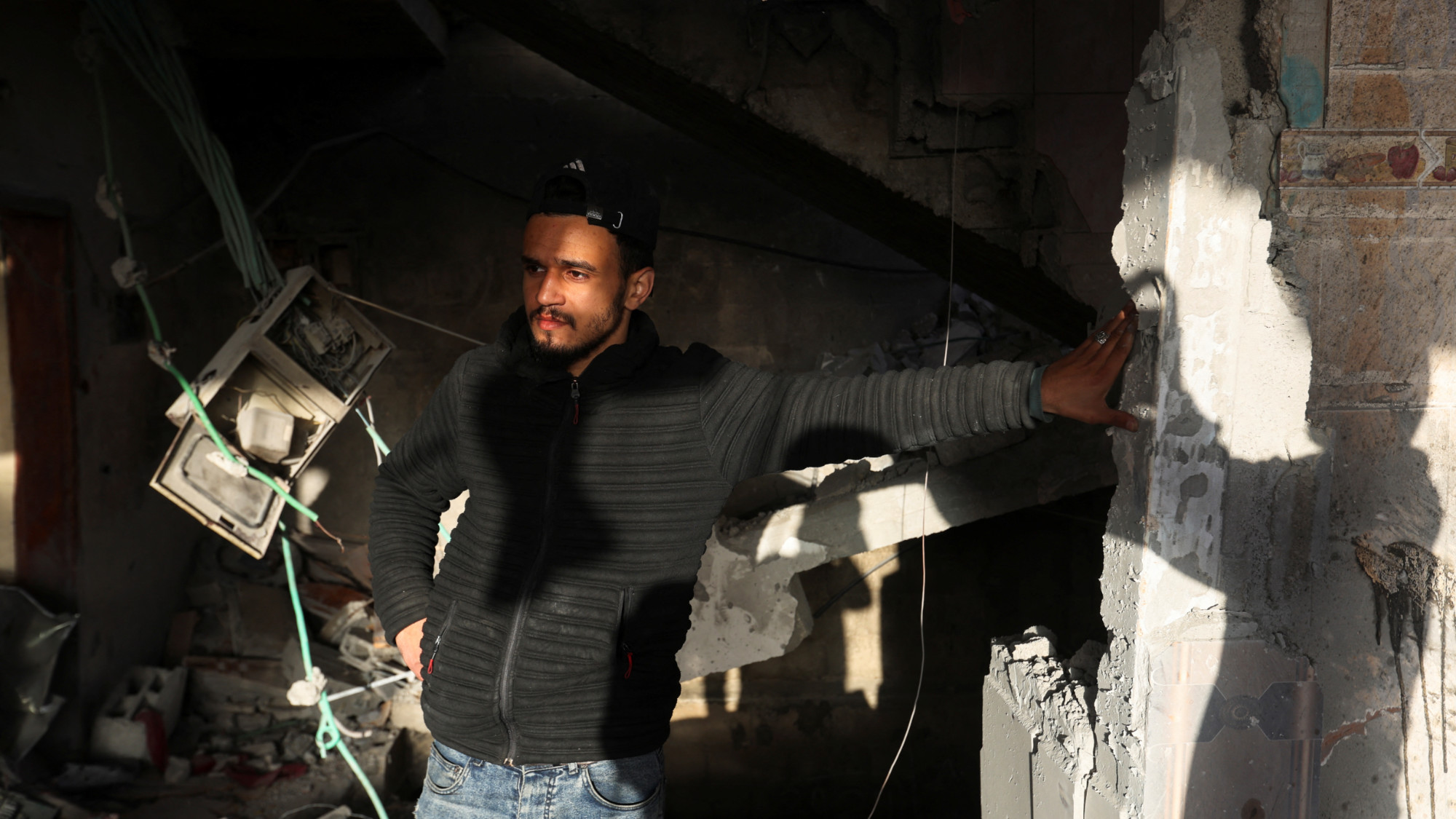 A Palestinian man stands at the site of an Israeli strike in Rafah in the southern Gaza Strip 10 January 2024 (Ibraheem Abu Mustafa/Reuters)