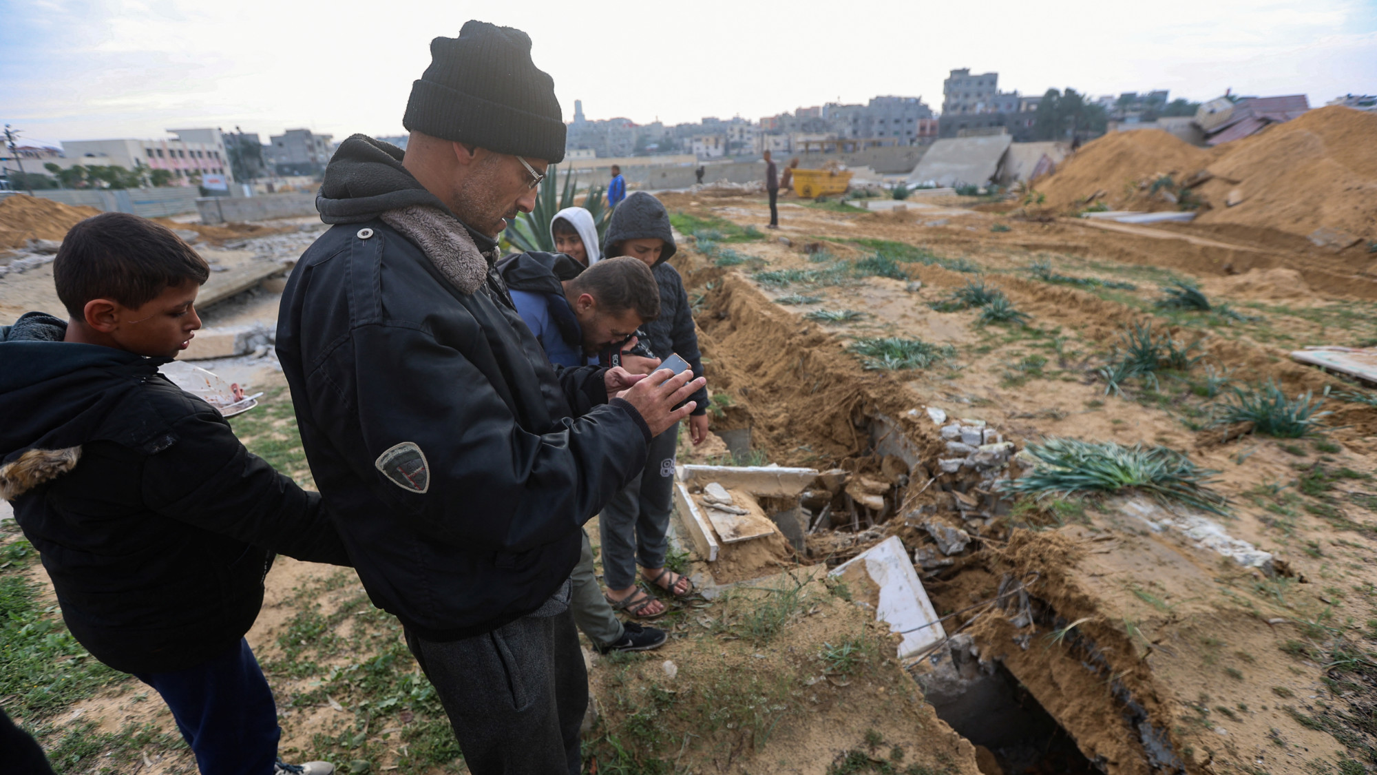 Palestinians check damaged graves at a cemetery following an Israeli raid in Khan Younis in the southern Gaza Strip 17 January 2024 (Ahmed Zakot/Reuters)