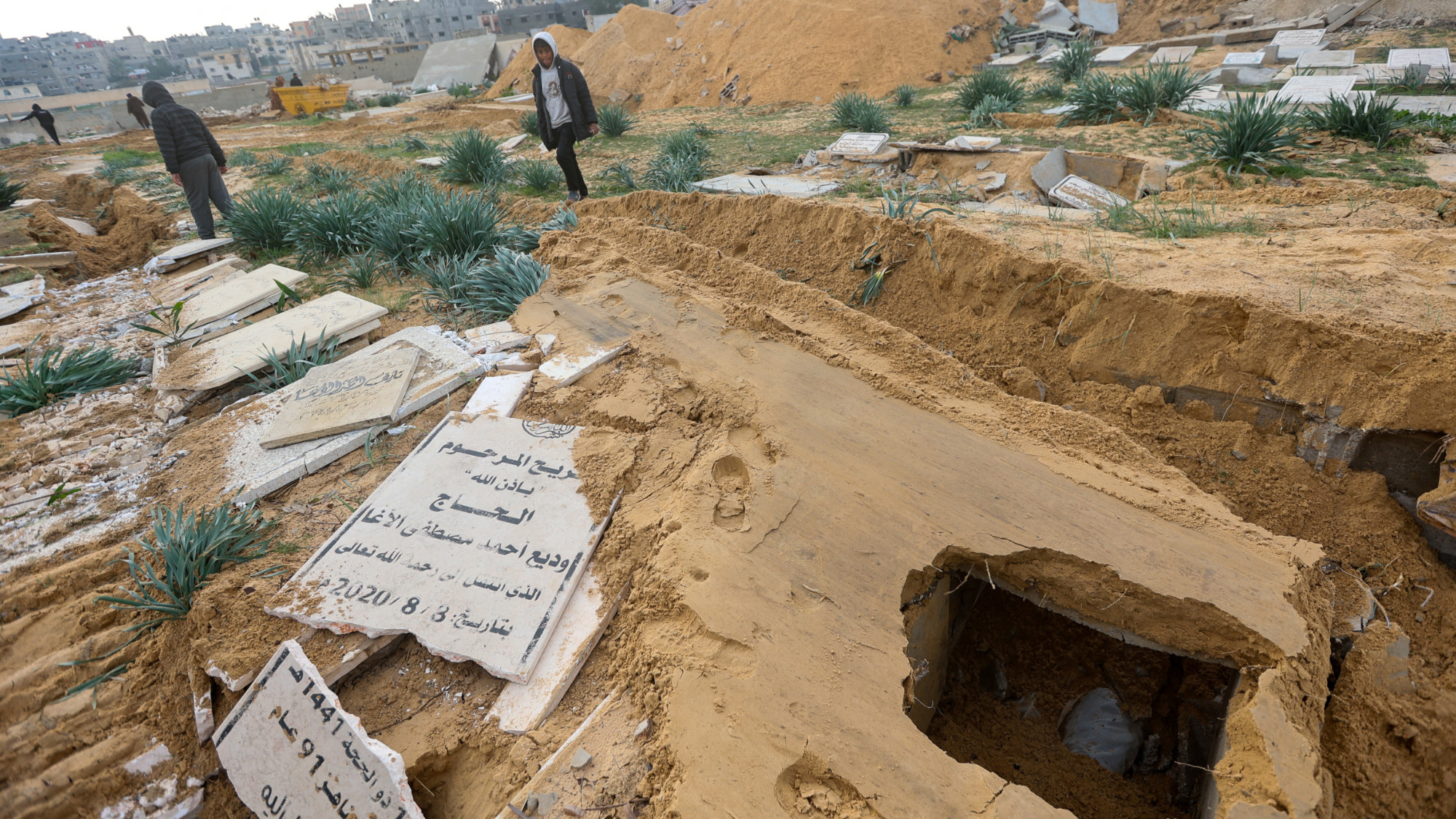 Palestinians check damaged graves at a cemetery following an Israeli raid in Khan Younis in the southern Gaza Strip 17 January 2024 (Ahmed Zakot/Reuters)