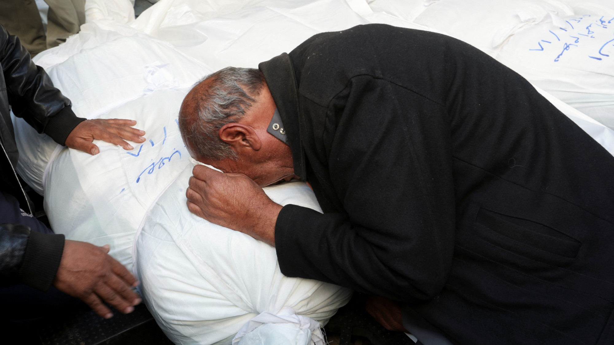A mourner grieves next to the bodies of Palestinians killed in an Israeli strike in Rafah in the southern Gaza Strip 18 January 2024 (Ibraheem Abu Mustafa/Reuters)