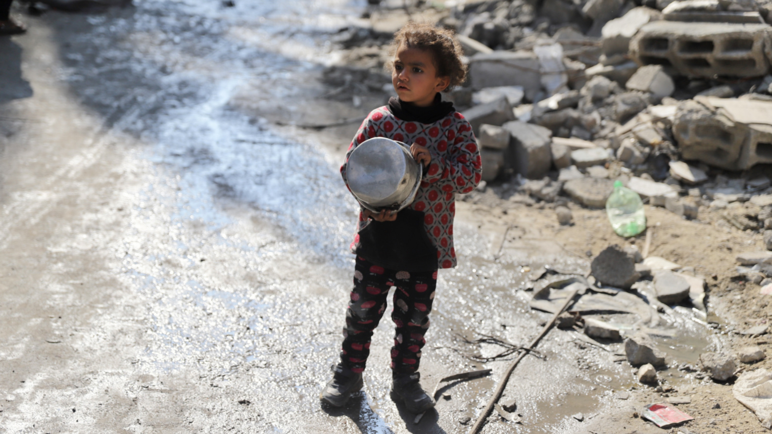 A girl holds her empty bowl in Gaza City (Mohammed al-Hajjar/MEE).