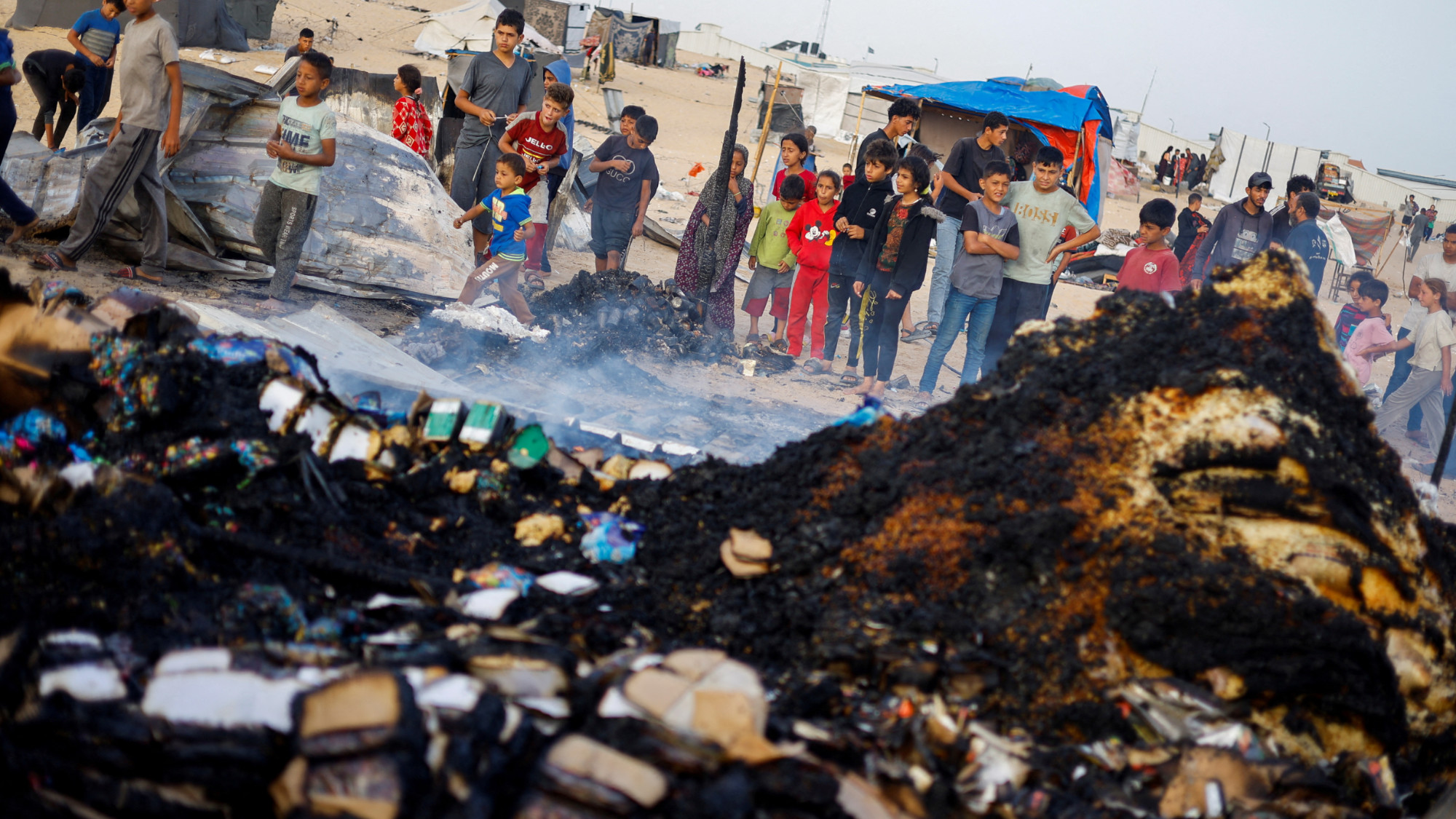 Palestinian children look at the damages at the site of an Israeli strike on a camp area for internally displaced people in Rafah on 27 May 2024 (Reuters/Mohammed Salem)