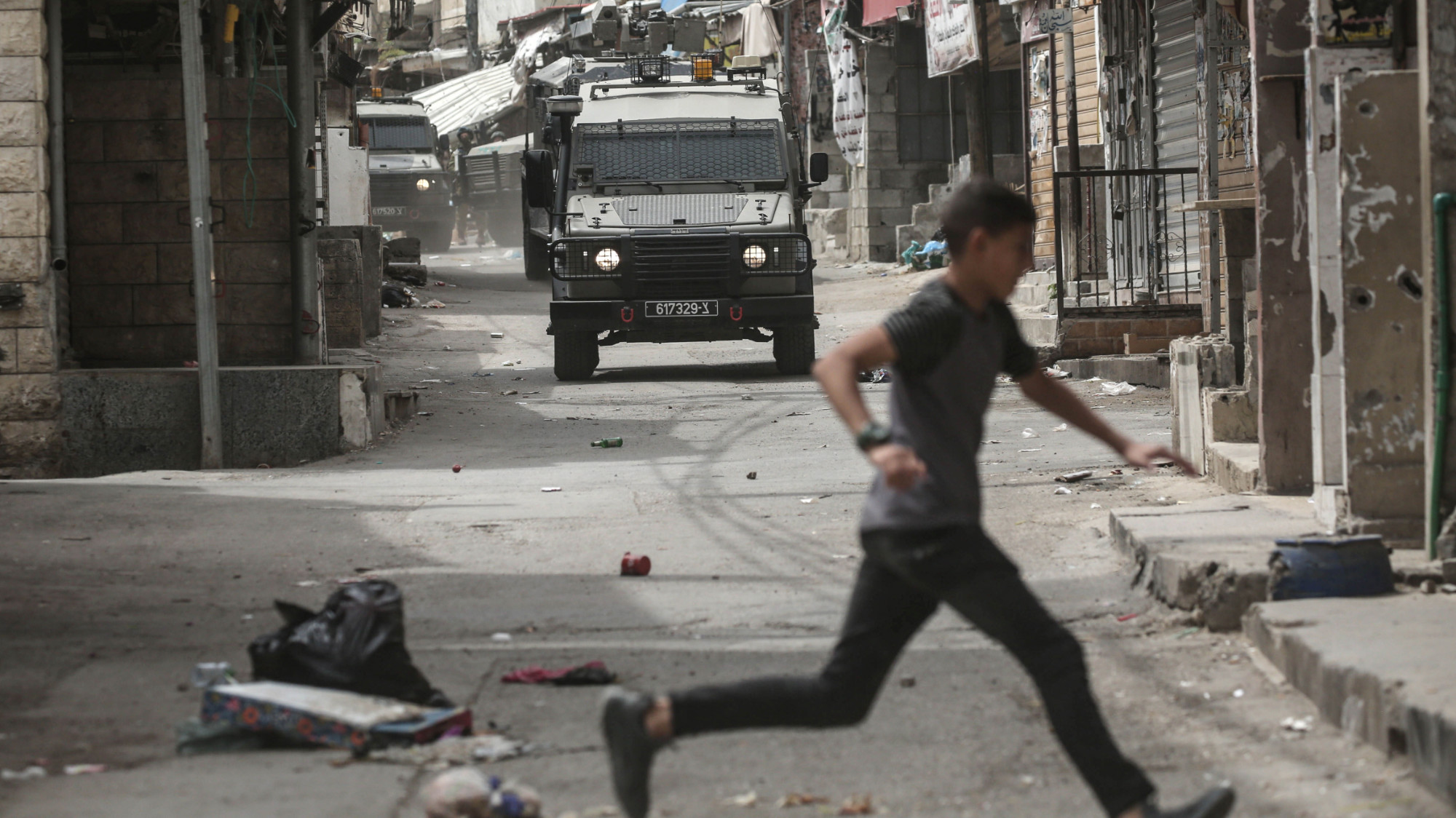 A Palestinian runs away from an Israeli military vehicle during a raid on the Balata refugee camp in the occupied West Bank on 9 April 2025 (Nasser Ishtayeh/SOPA Images via Reuters)