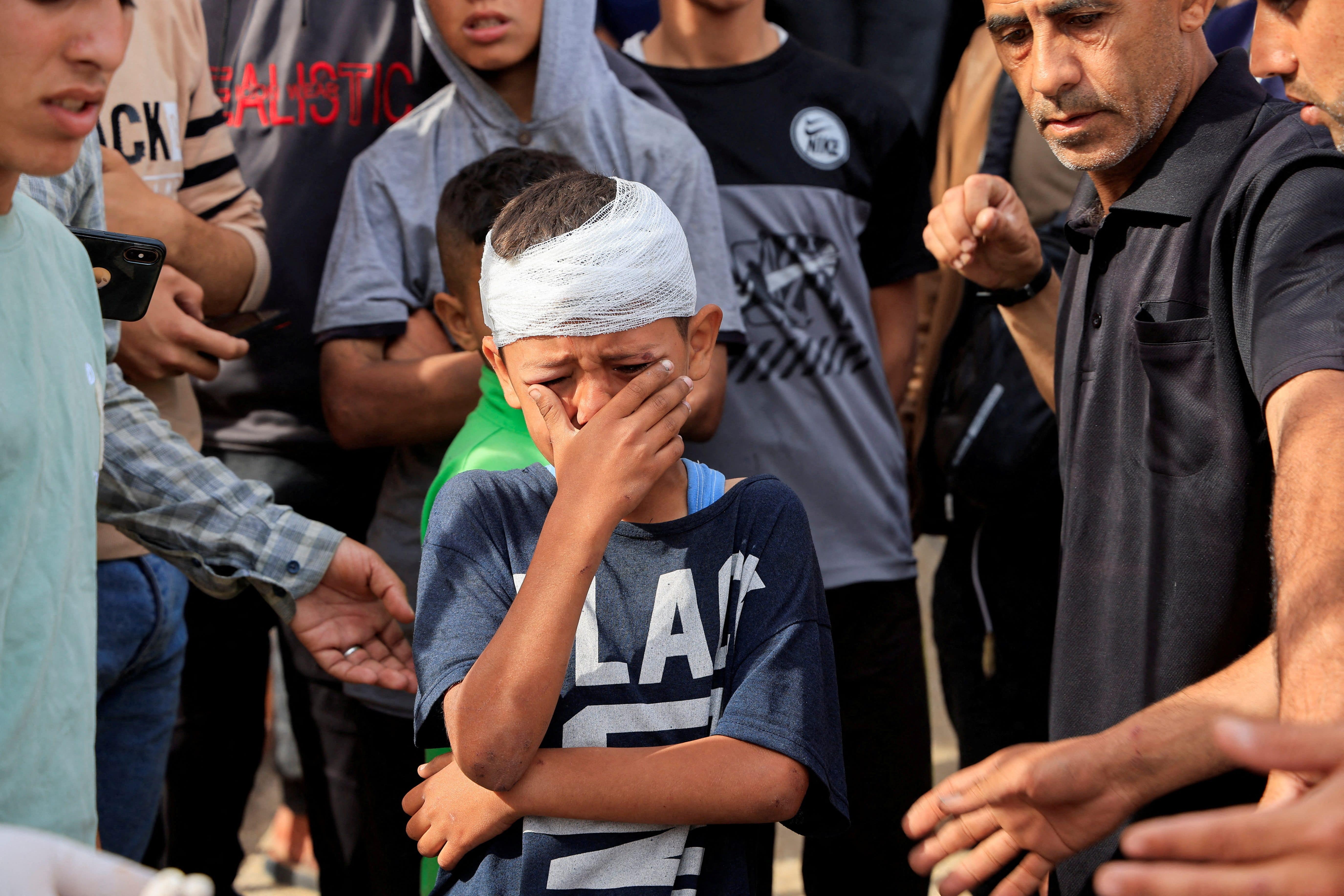 Injured Palestinian child, Yousef Al-Bayouk, weeps over his brothers, Moath and Moataz, who were killed in Israeli strikes, as mourners attend their funeral, at Nasser hospital in Khan Younis, southern Gaza Strip, May 15, 2025. REUTERS