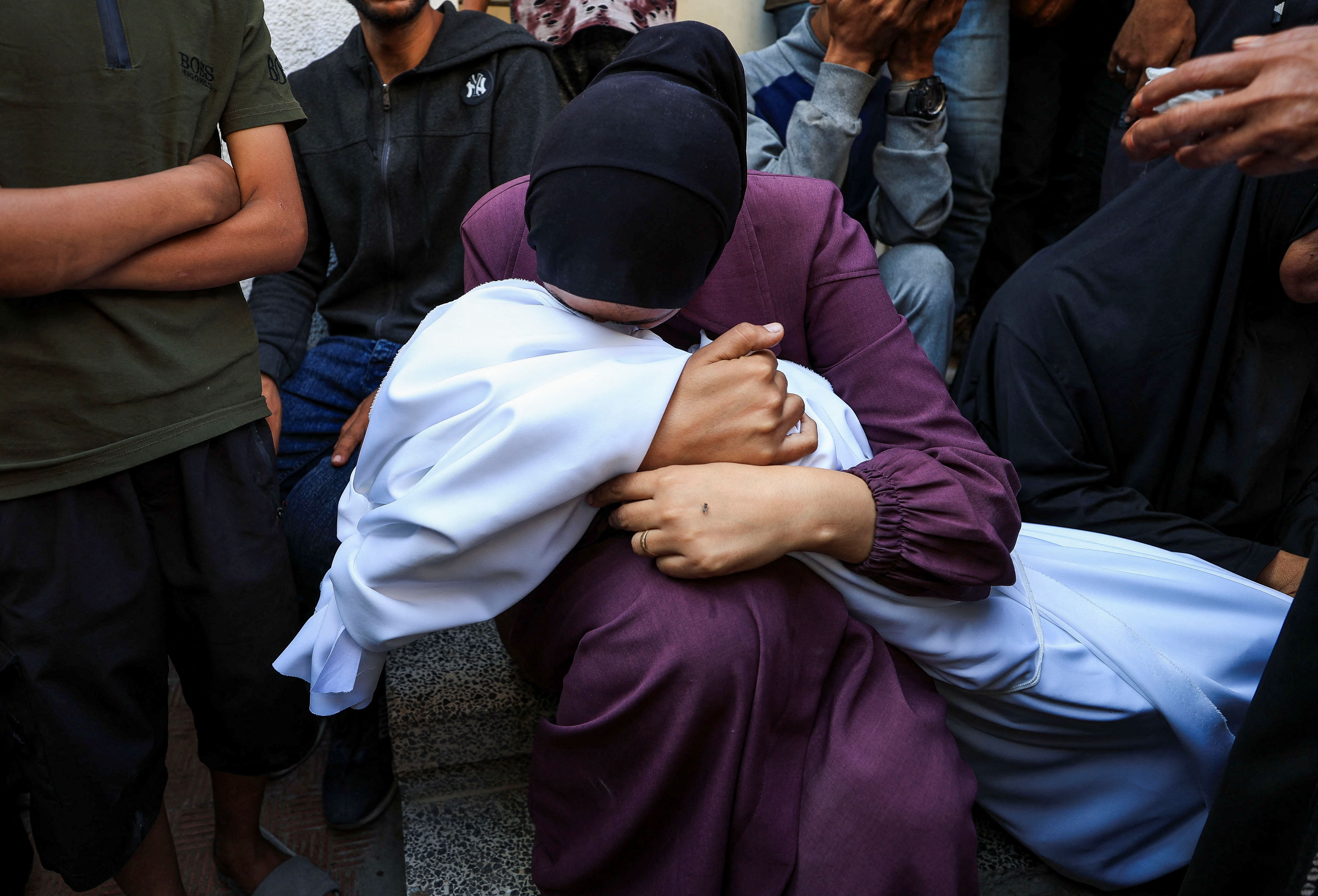 A woman holds the body of a Palestinian who was killed, according to medics, in Israeli strikes, as mourners gather during the funeral at Al-Shifa hospital, in Gaza City, June 4, 2025. REUTERS