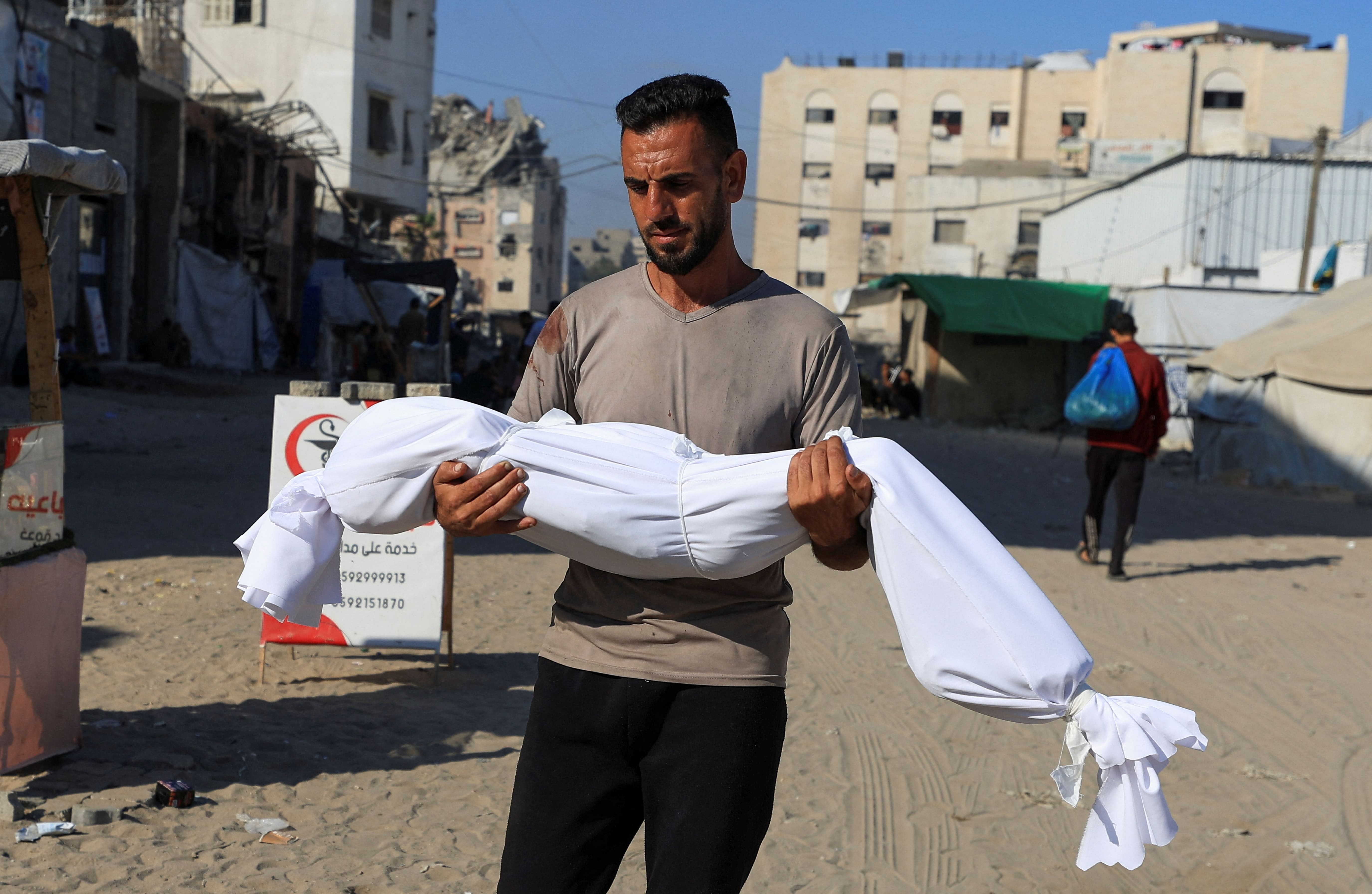 A man carries a body of a child, during the funeral of Palestinians, who, according to Gaza's health ministry, were killed in an Israeli air strike on a house, outside Al-Shifa Hospital, in Gaza City, June 25, 2025.