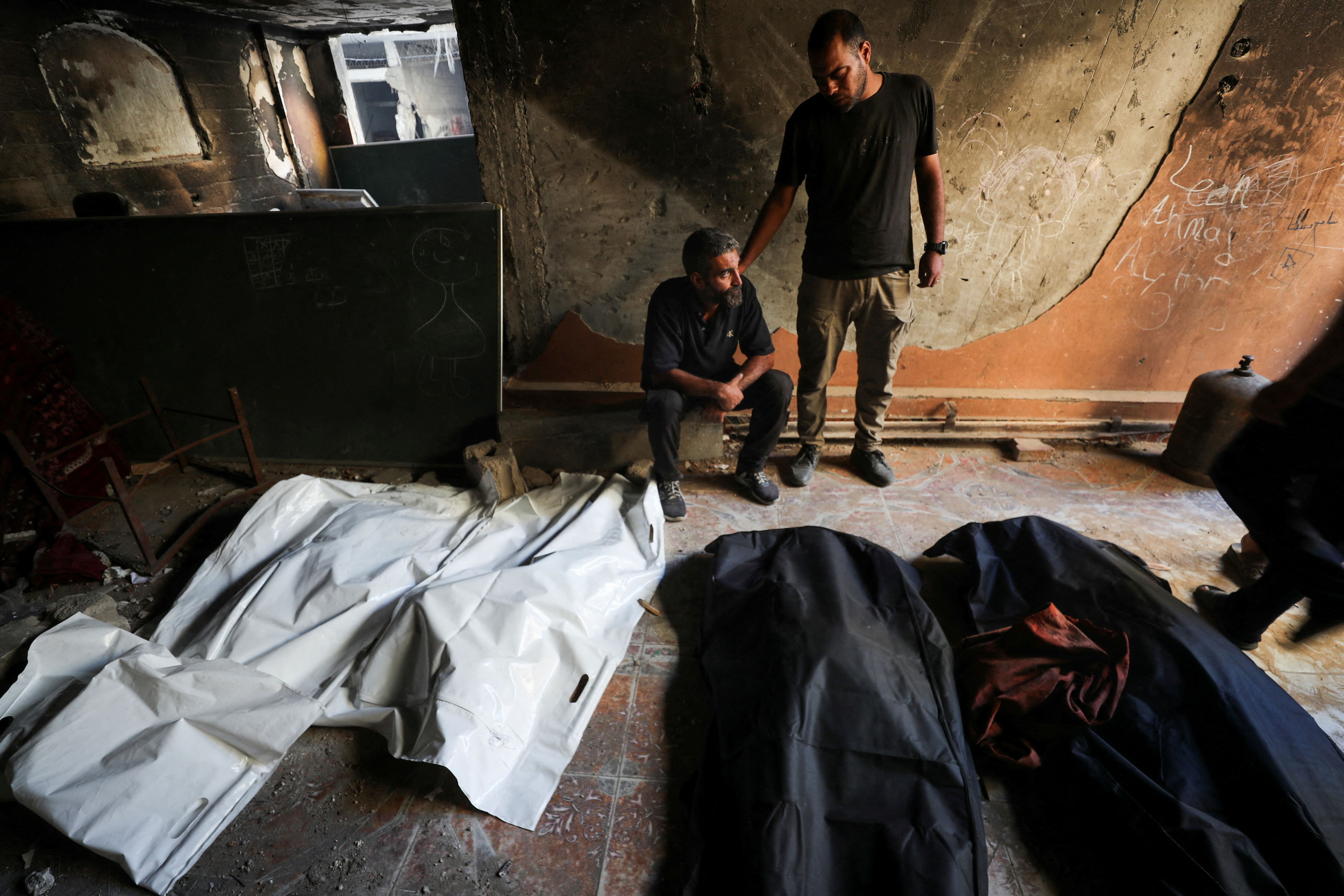 Palestinians react next to the bodies of people killed at the site of an overnight Israeli strike on a house, in Gaza City, July 6, 2025. REUTERS