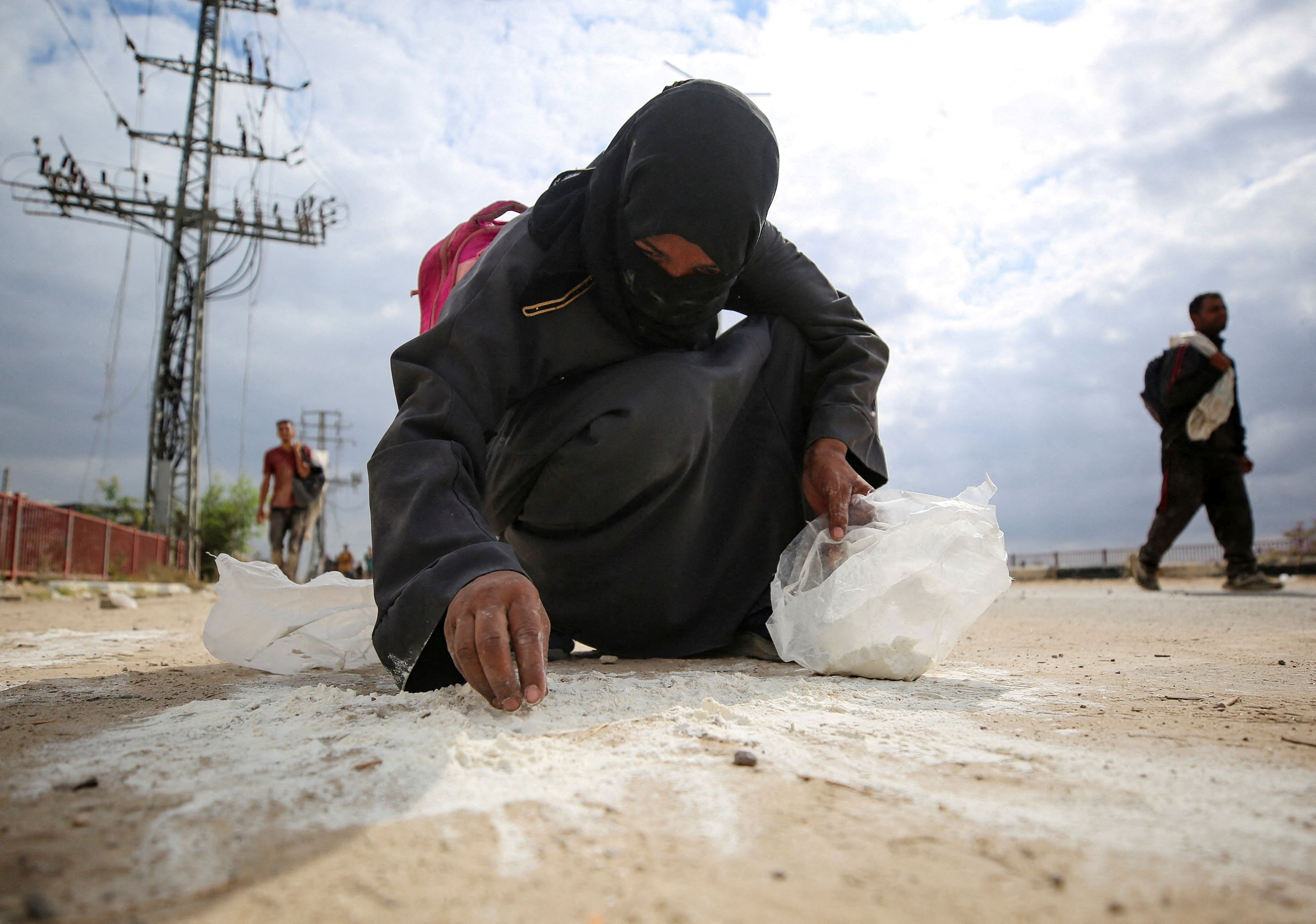 A woman collects flour from the ground as Palestinians receive aid supplies from the U.S.-backed Gaza Humanitarian Foundation (GHF), in the central Gaza Strip, August 1, 2025. REUTERS