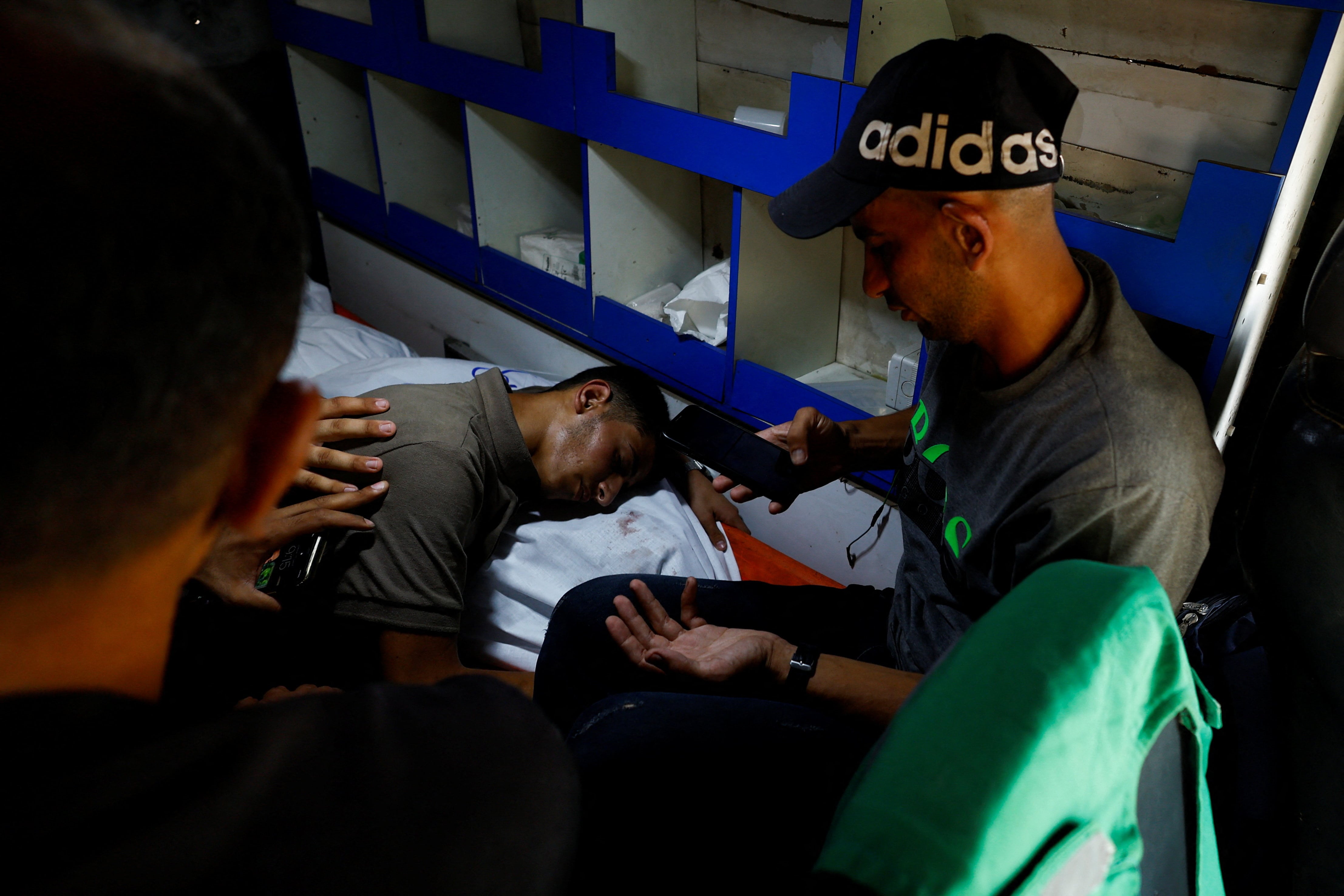 Palestinians react next to the body of Al Jazeera journalist Anas Al Sharif, who was killed along with four colleagues in an Israeli airstrike, inside an ambulance in Gaza City August 11, 2025.