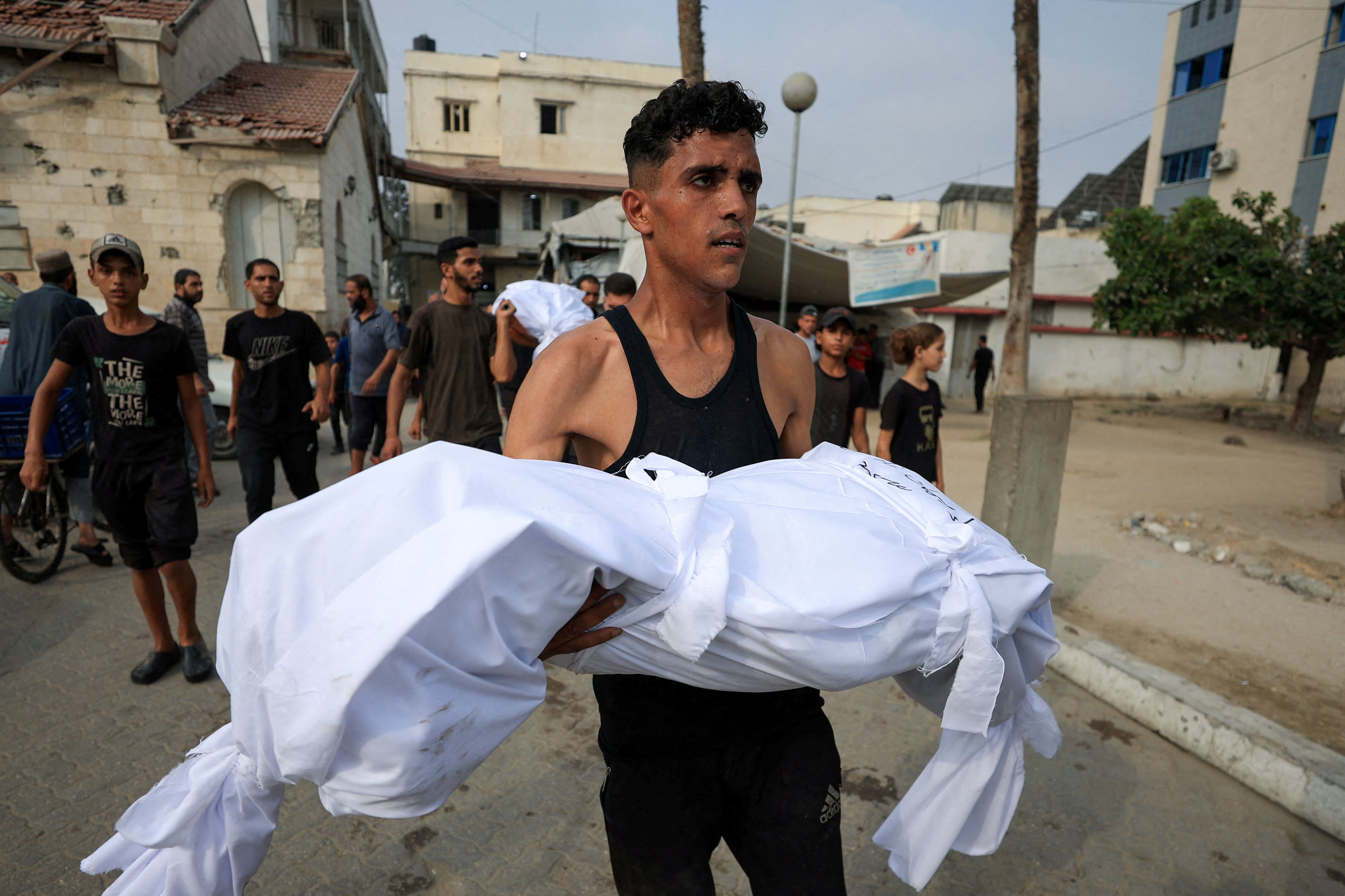 Palestinian man Ahmed Saad carries the body of his sister Iman, during the funeral of Palestinians who were killed in Israeli strikes, according to medics, at Al-Ahli Arab Hospital in Gaza City August 12, 2025. R