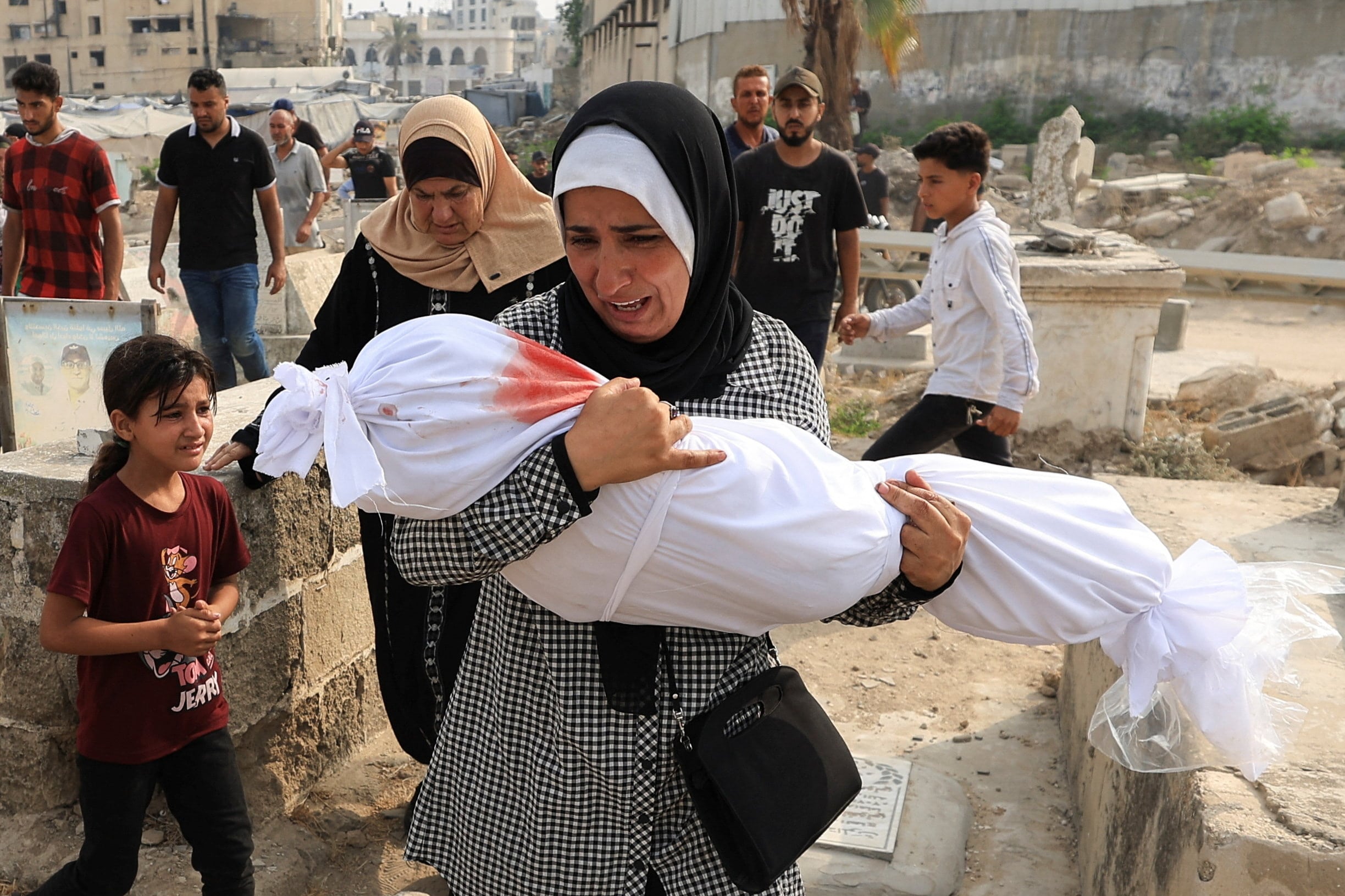 Palestinian woman Soha Tafesh carries the body of her granddaughter Sarah Abu Daf, who was killed in an early morning Israeli strike on a house, according to medics, at a cemetry in Gaza City, August 13, 2025. REUTERS