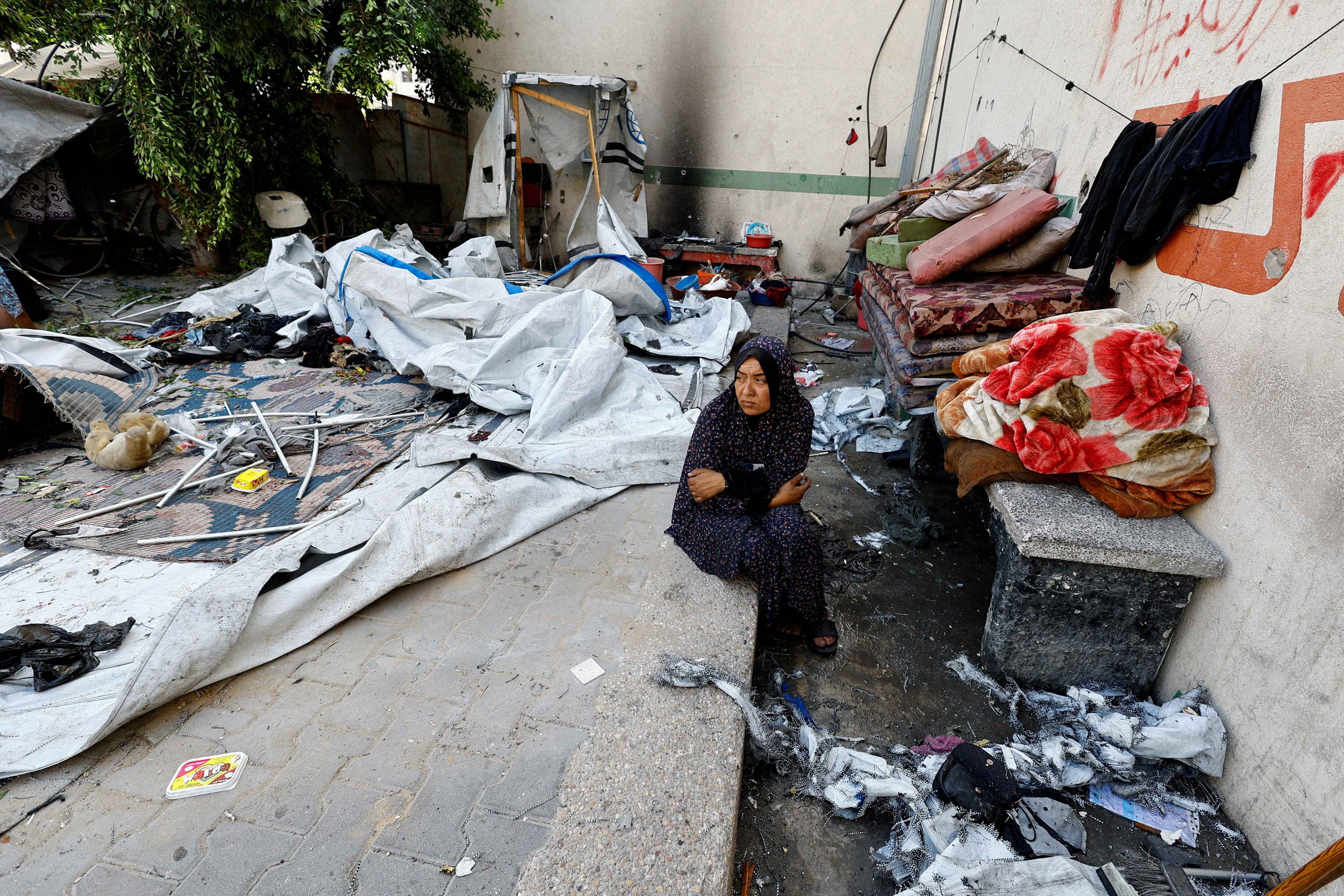 A Palestinian woman sits at the site of a Friday Israeli strike on a school that was sheltering displaced people, in Gaza City, August 16, 2025. REUTERS